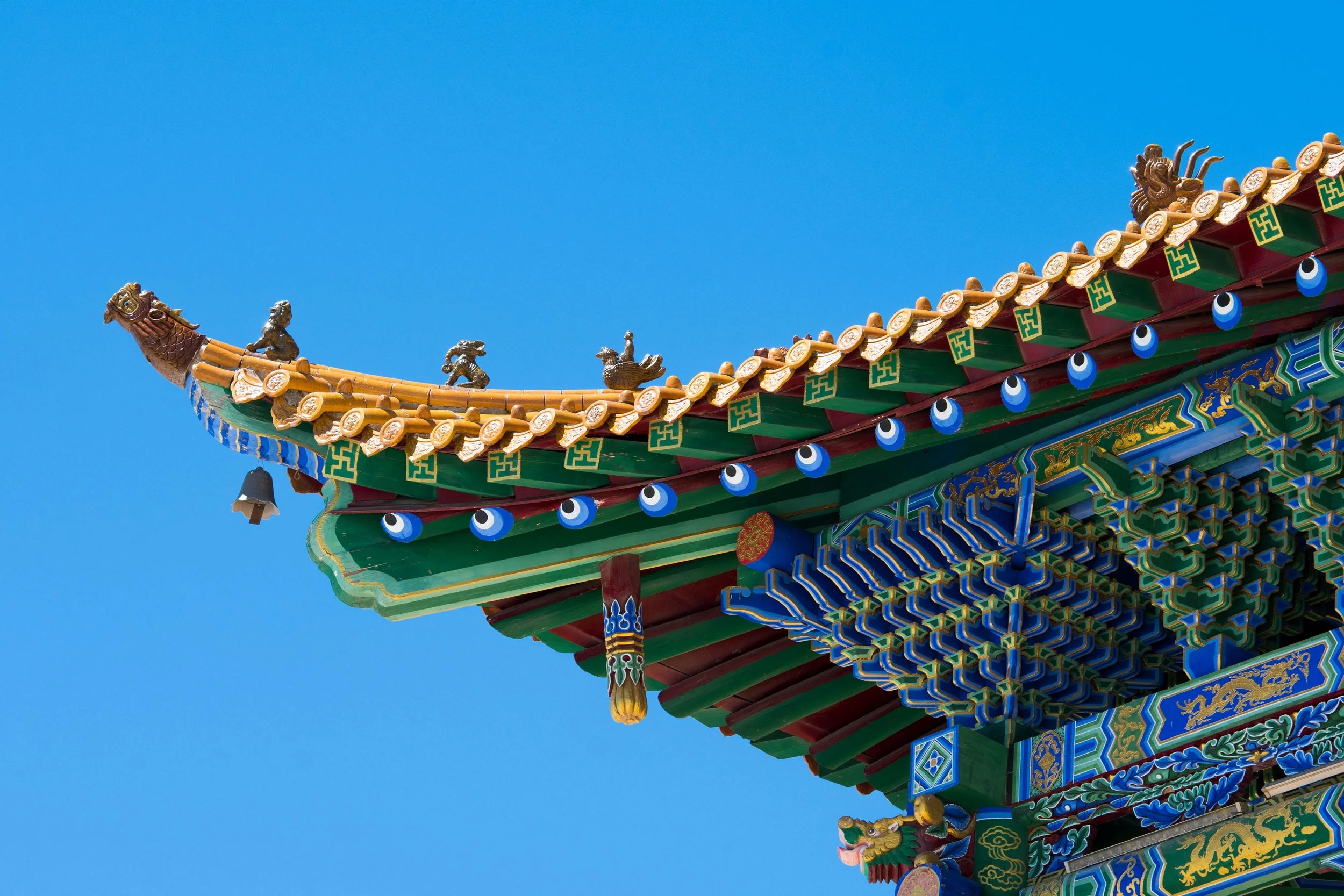 Colorful traditional Chinese temple roof with intricate designs and decorations against clear blue sky.