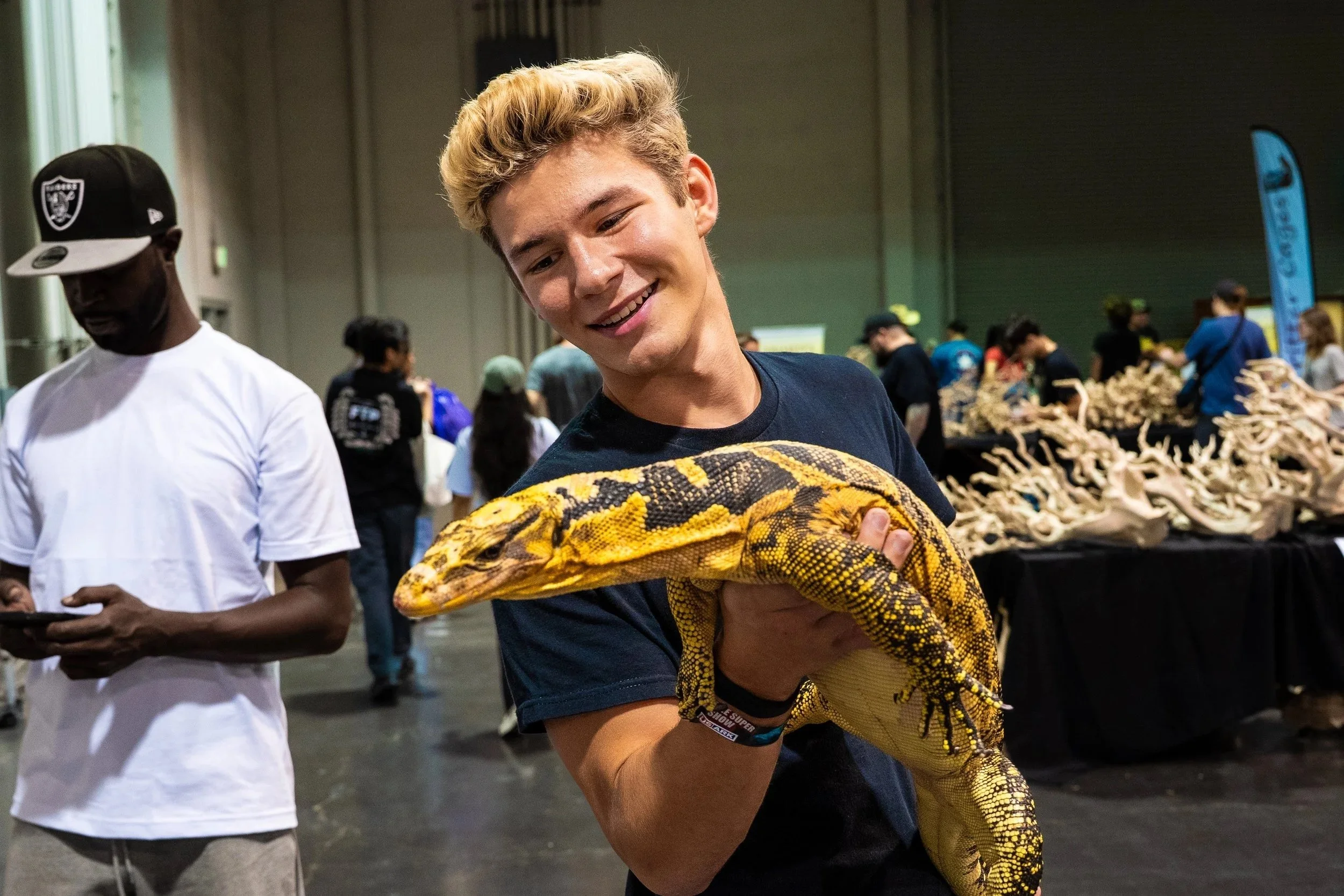 Adriano Bracamontes, founder of Black Venom Coffee Co. holding a water monitor at the Anaheim Reptile Super Show, 2025.