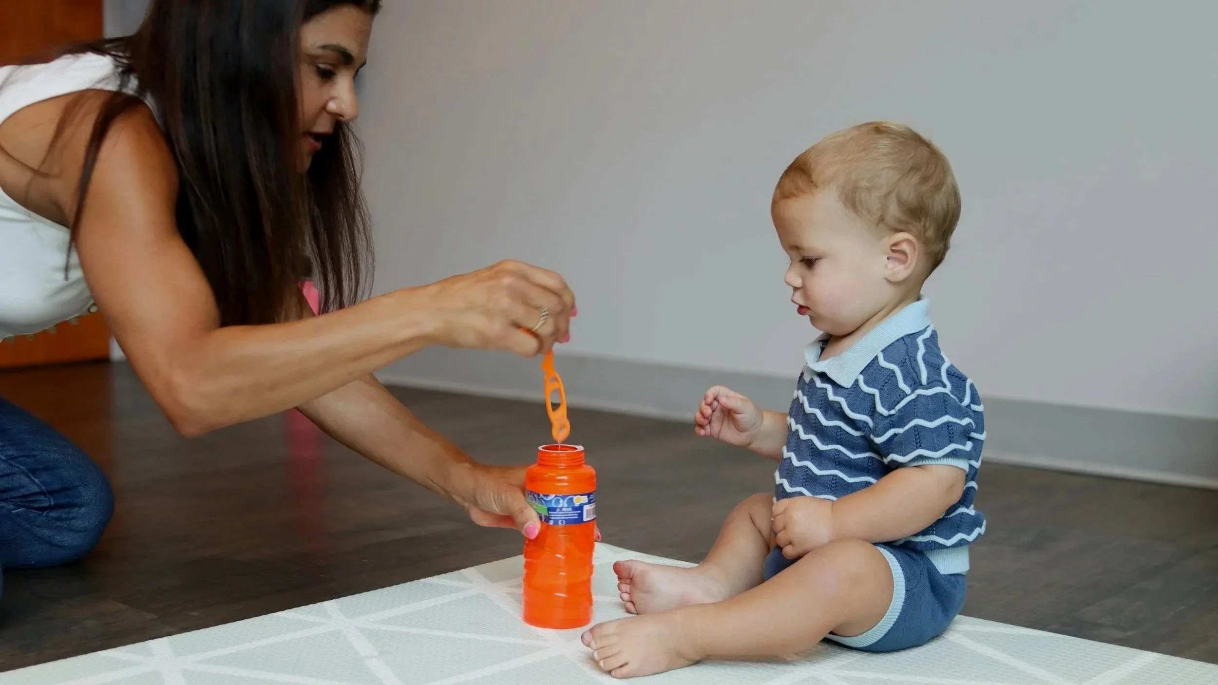 Owner and founder Andrea Callanen helps a one year old boy sit independently and blow bubbles in the Looking Ahead office. 
