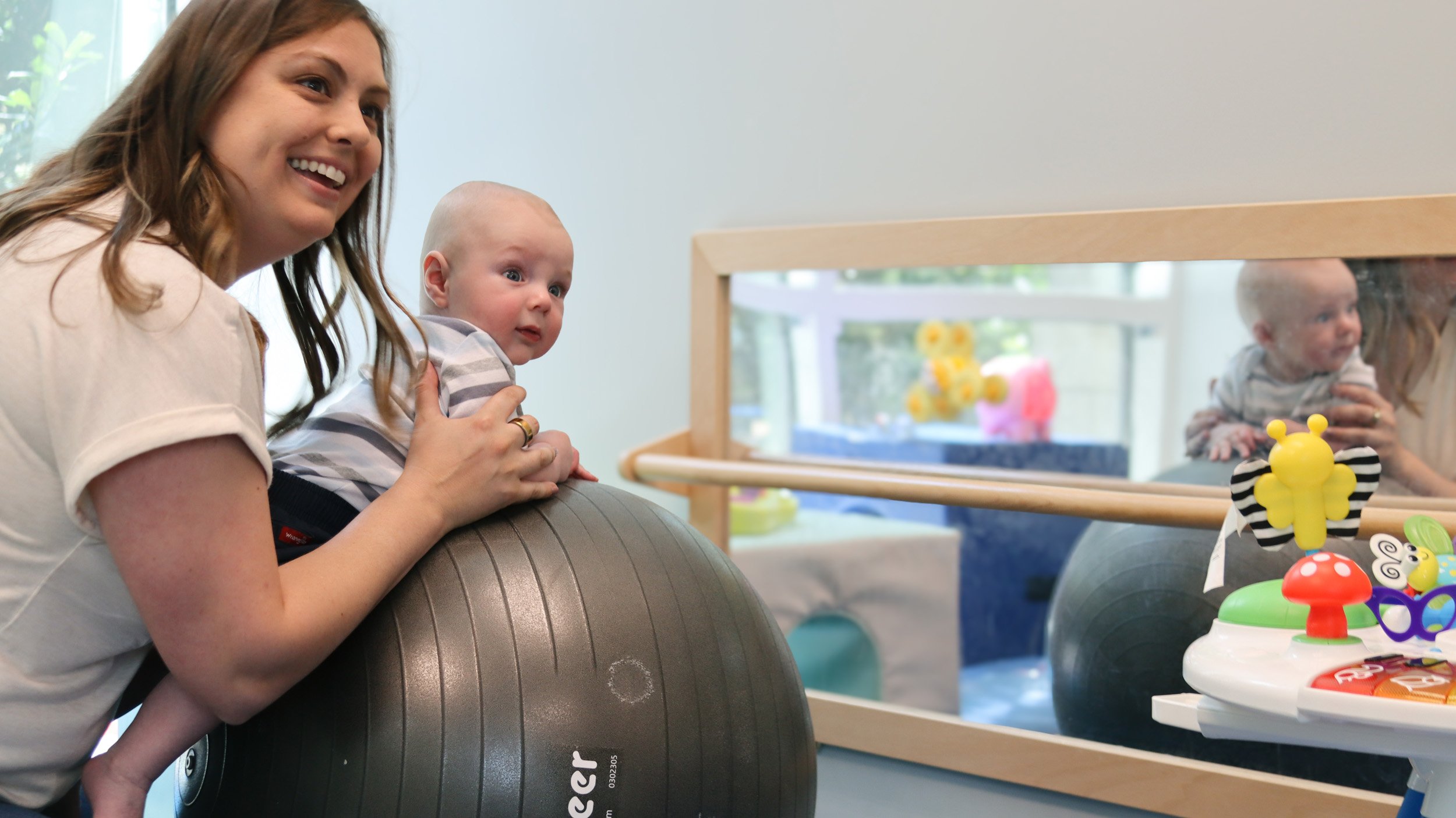 A pediatric therapist helps an infant do tummy time on a ball as part of his torticollis and plagiocephaly treatment at Looking Ahead in Franklin, TN