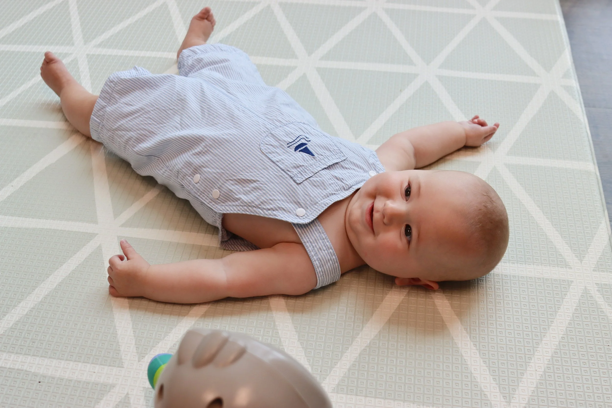 A baby smiles on a mat as he is evaluated for torticollis and plagiocephaly at the Looking Ahead office in Franklin, TN