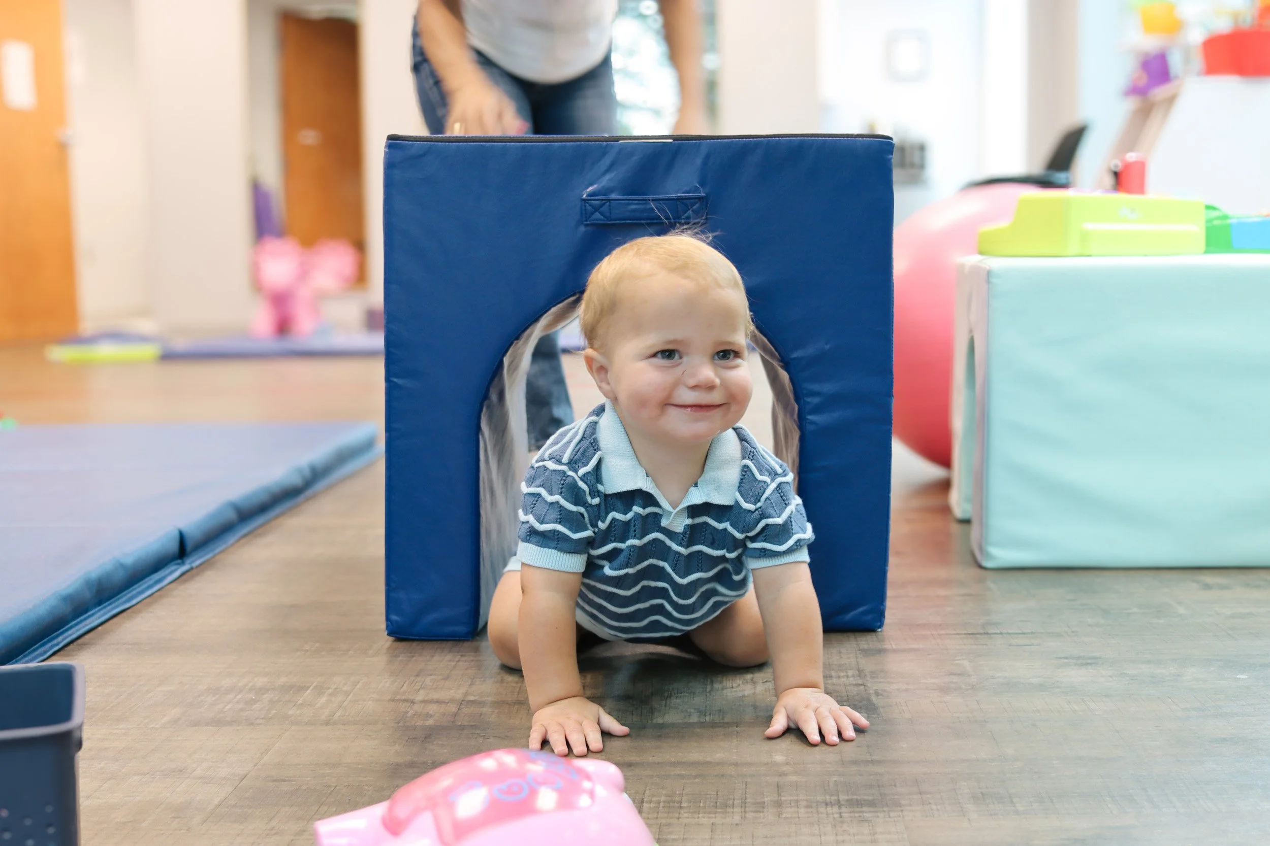 A baby crawls through a blue tunnel in Looking Ahead's Franklin, TN office.