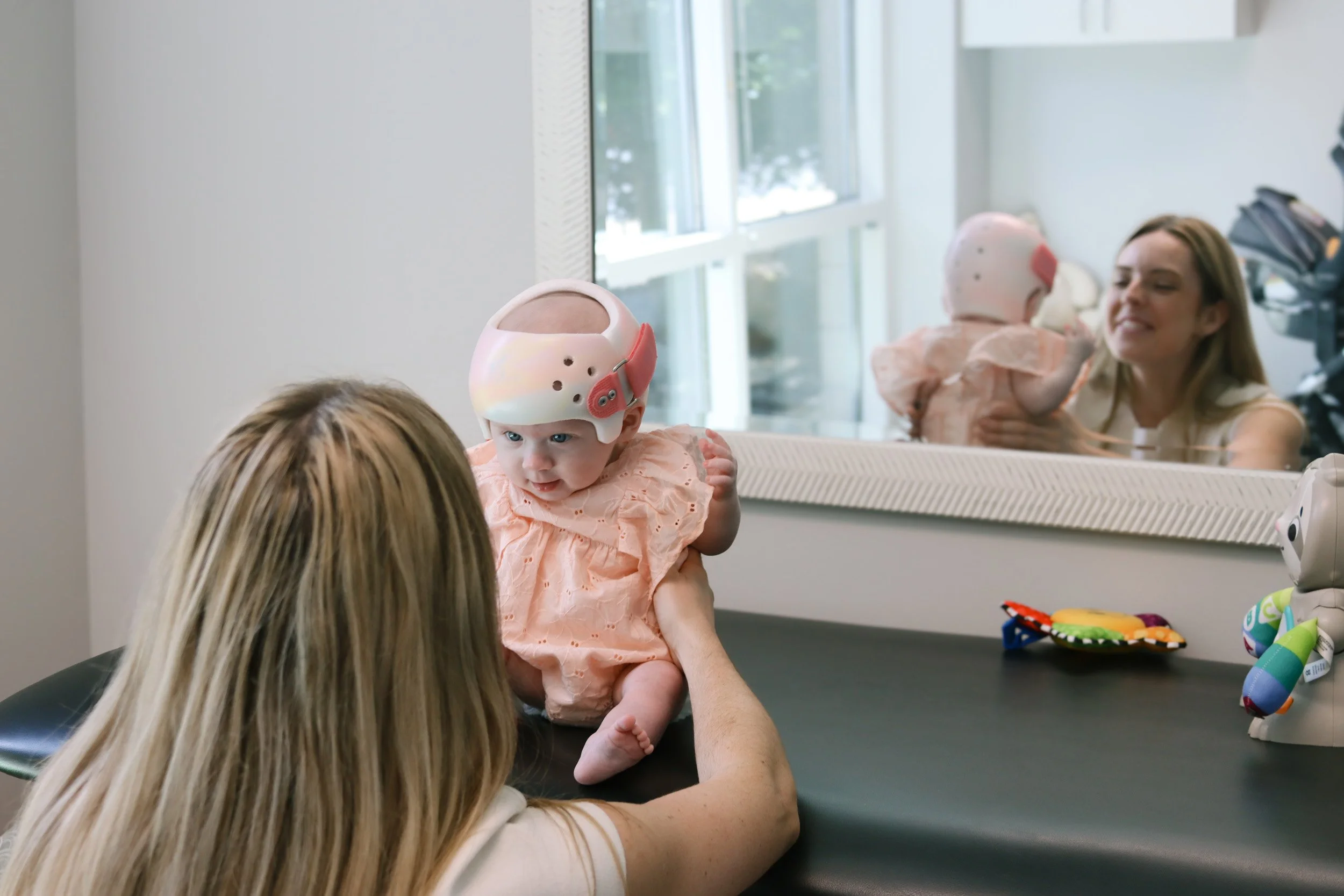 Dr. Emelia Baer holds a baby with a helmet to treat plagiocephaly