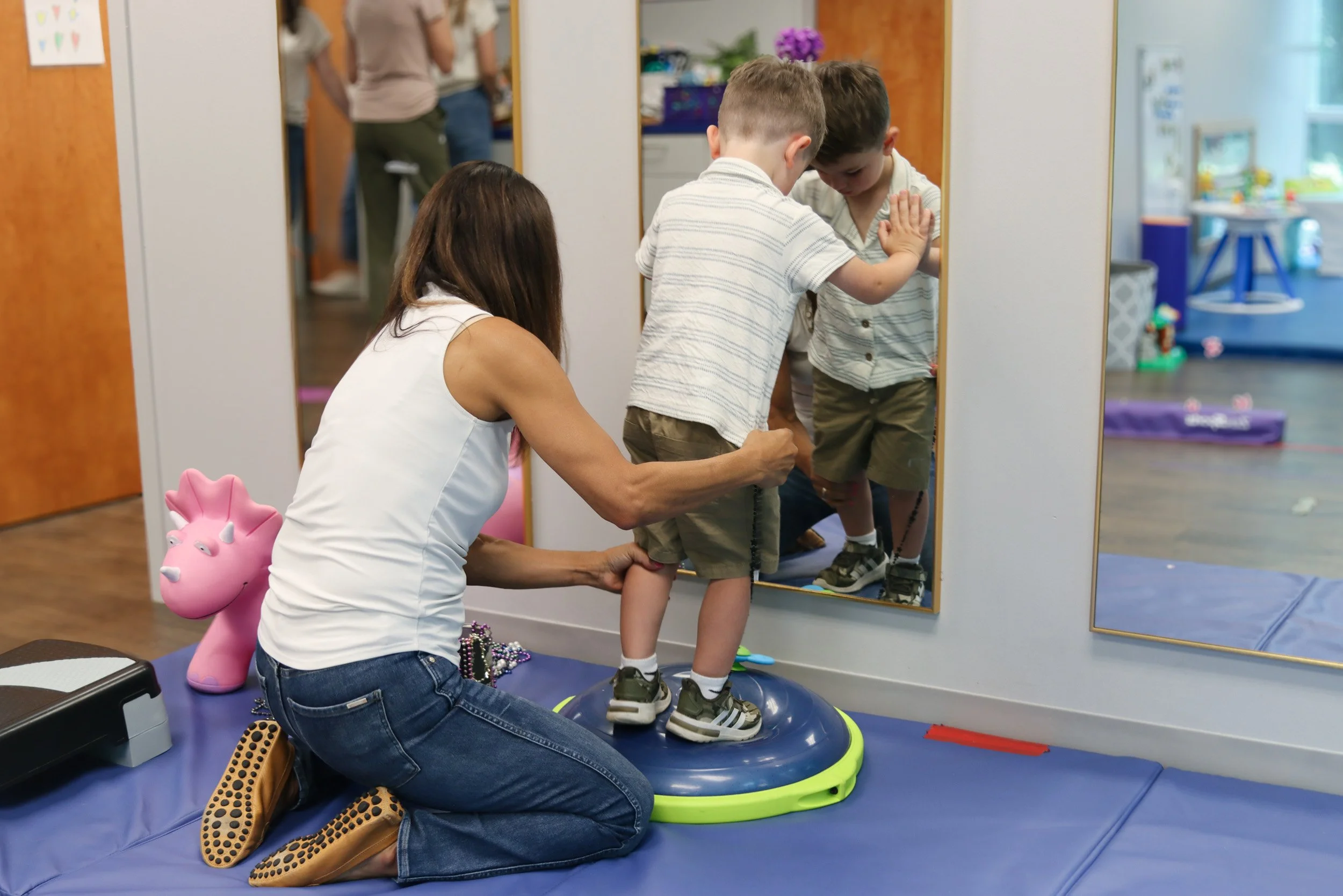 A young boy balances on a ball as part of an exercise supporting his gross motor development