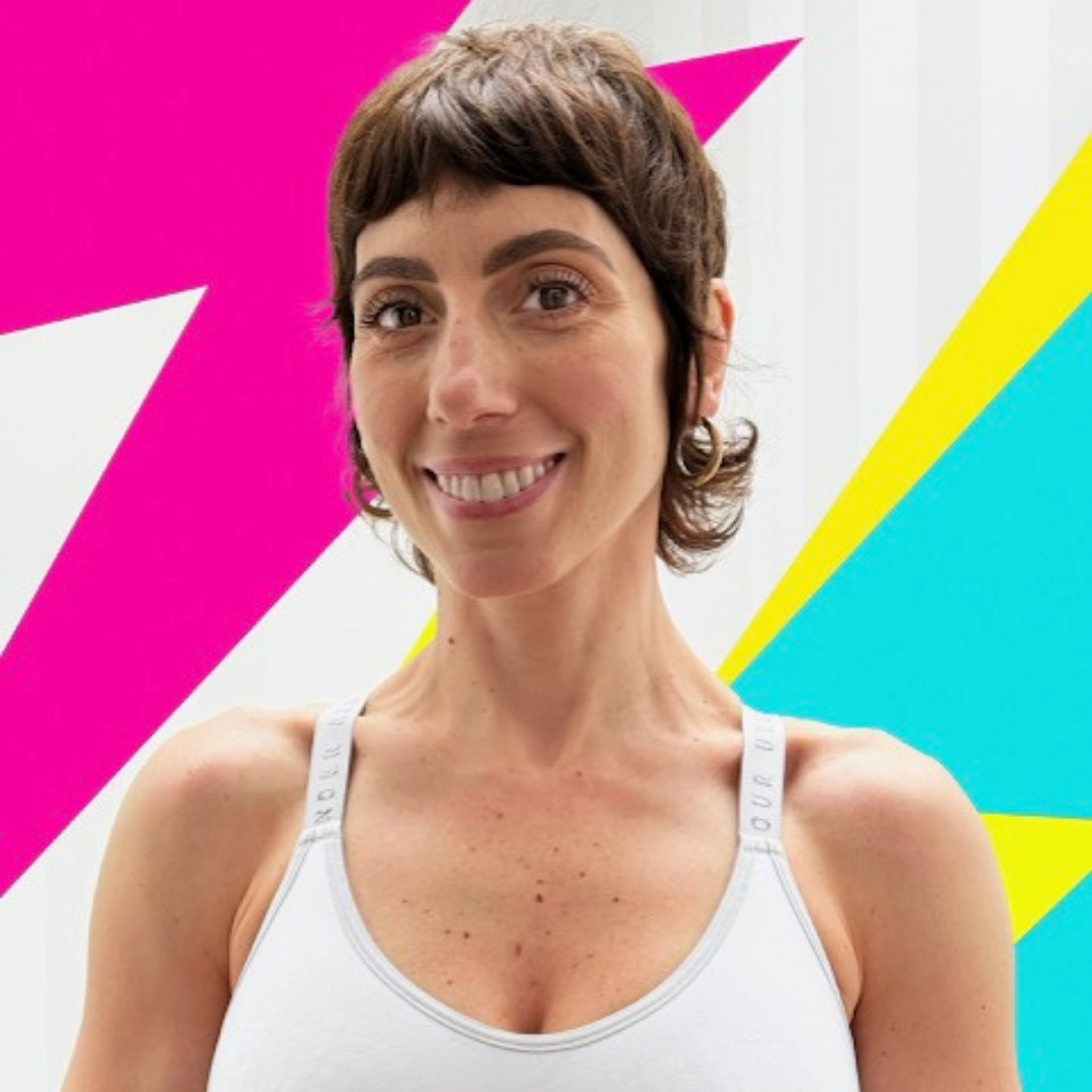A woman with short brown hair, hoop earrings, and a white top, smiling at the camera against a white background.