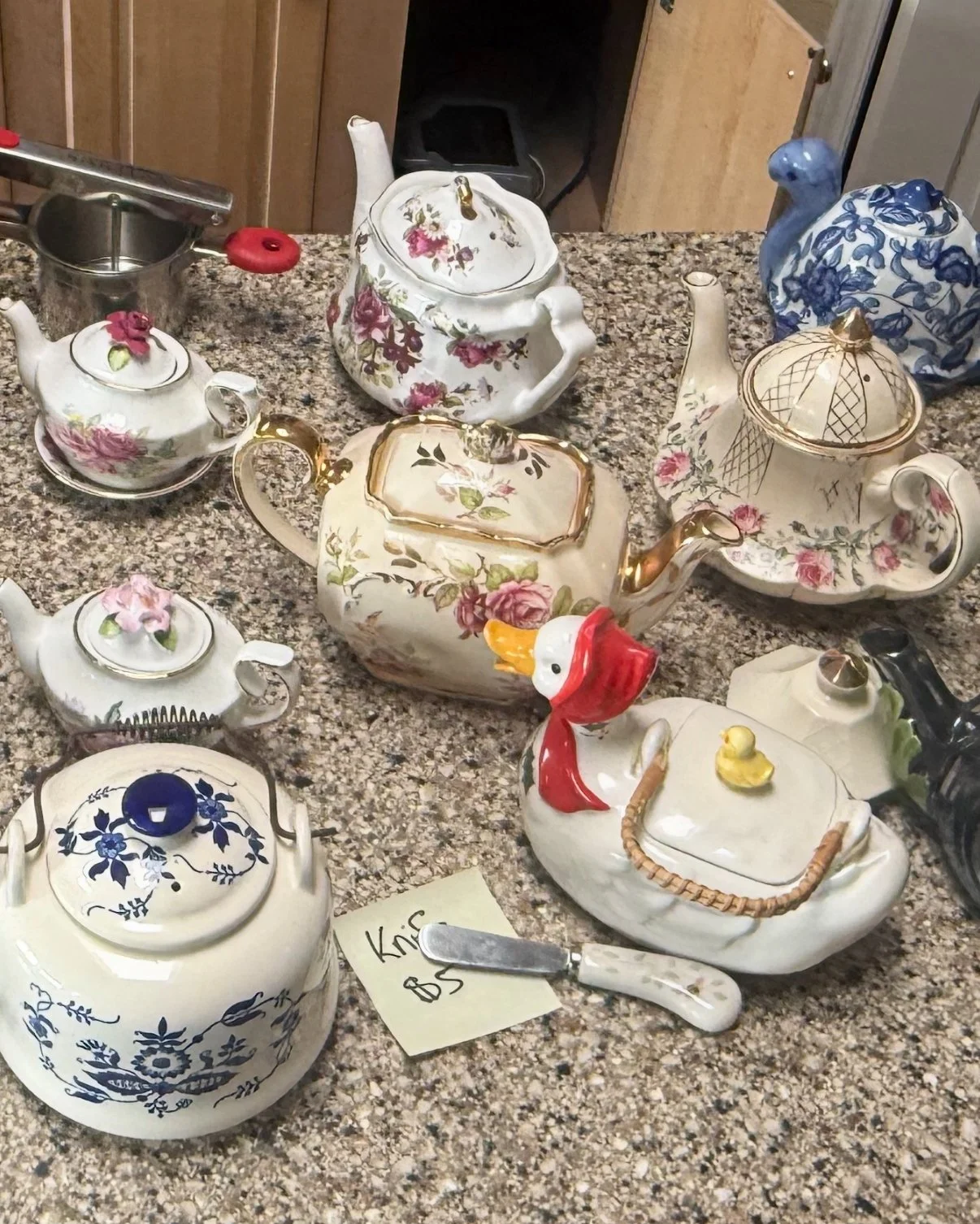Assorted decorative porcelain teapots and a duck figurine on a kitchen countertop.