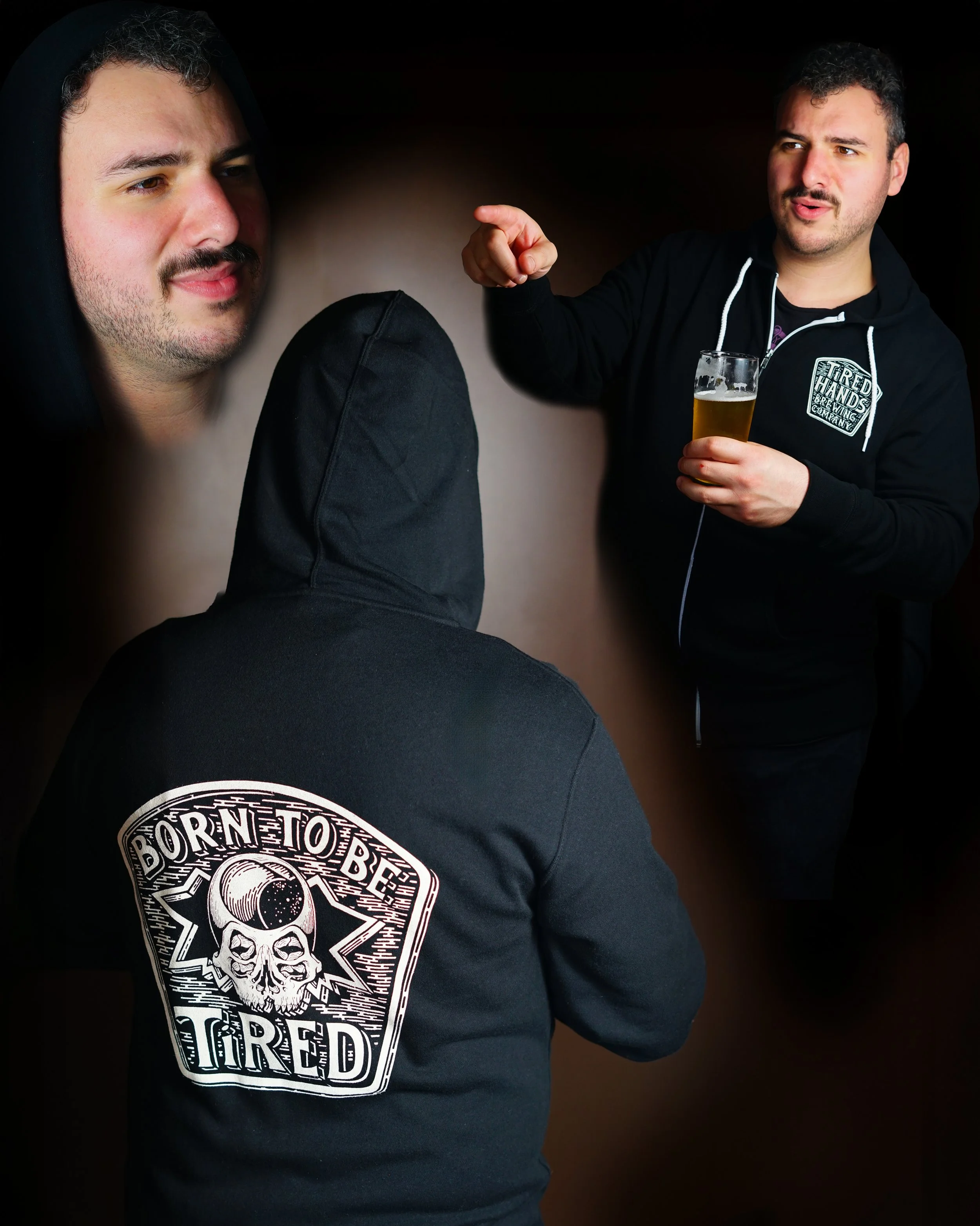 Three men, one with his back to the camera and wearing a black hoodie with a skull logo and the words 'Born to Be Tired,' and two facing each other, one holding a beer and pointing, the other listening. The background is dark.