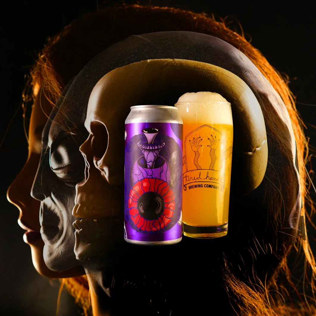 A surreal image of a woman's head in profile with her face blending into a skull. Two cans of beer are placed over the head, one on each side. The left can is purple with colorful abstract art, and the right can is yellow with a label from Tired Hands Brewing Company.