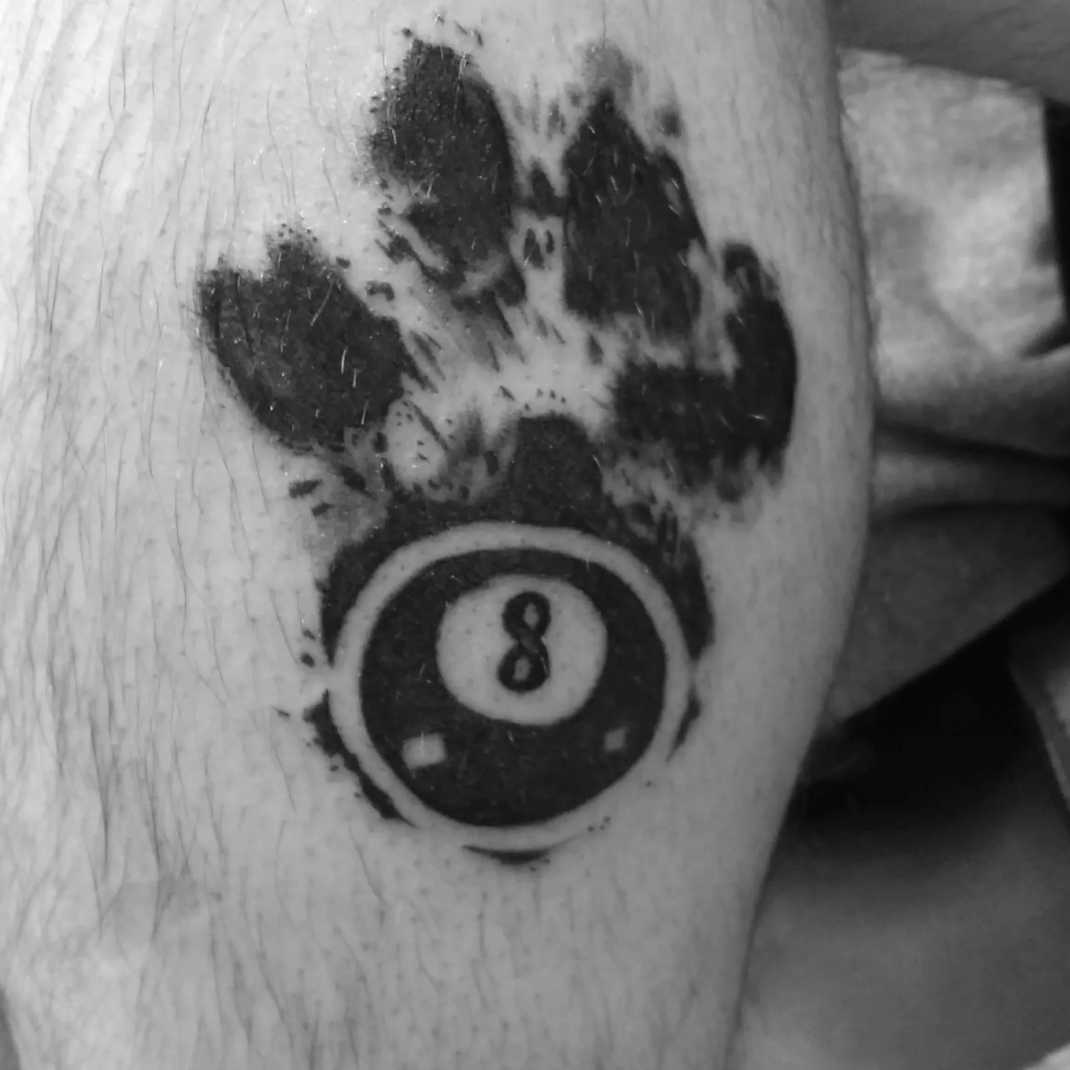 Tattoo of a puppy holding a pool ball with the number 8 on it.