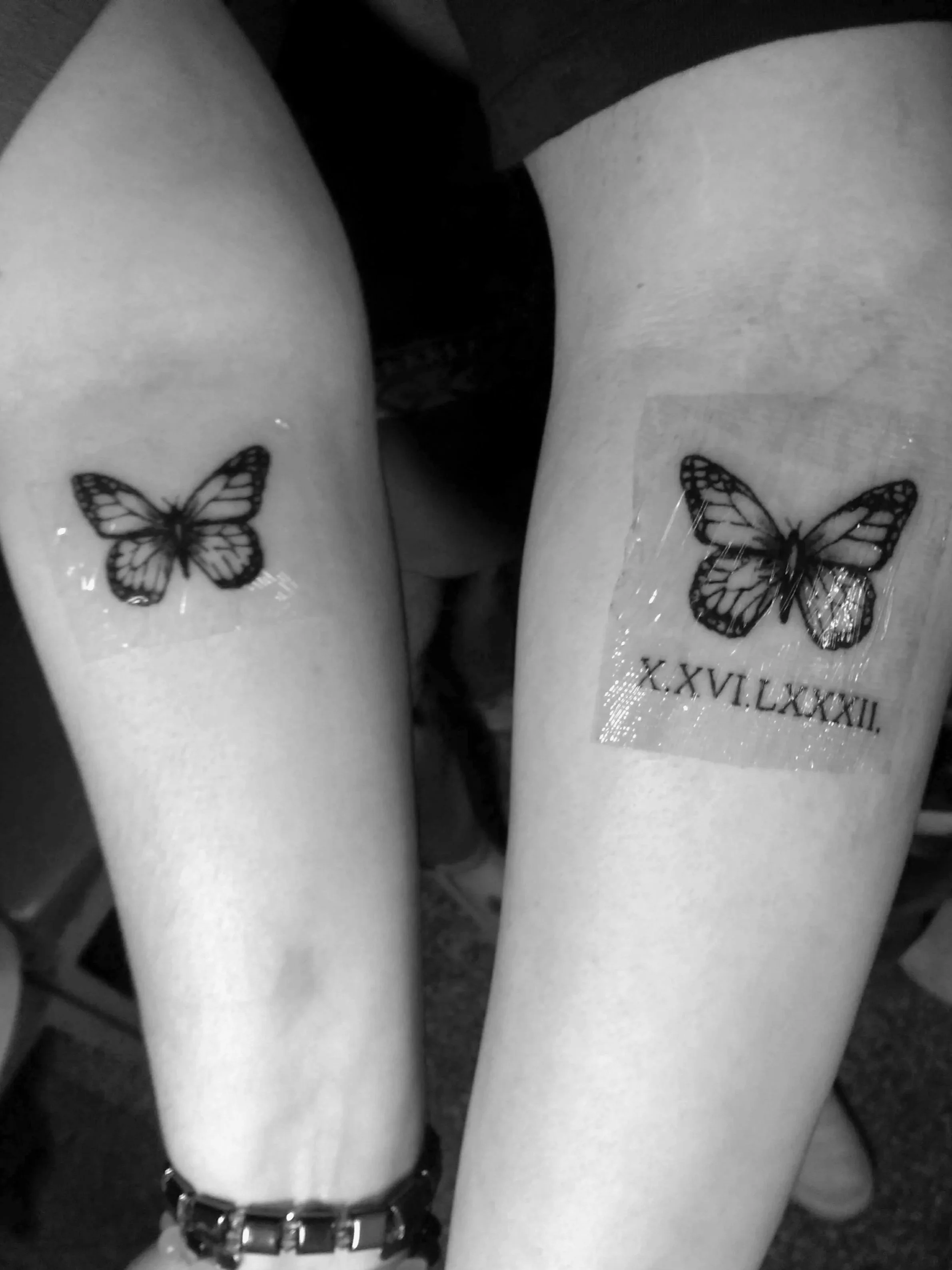 Tattoo of a butterfly on the left thigh and a butterfly with Roman numerals on the right thigh.