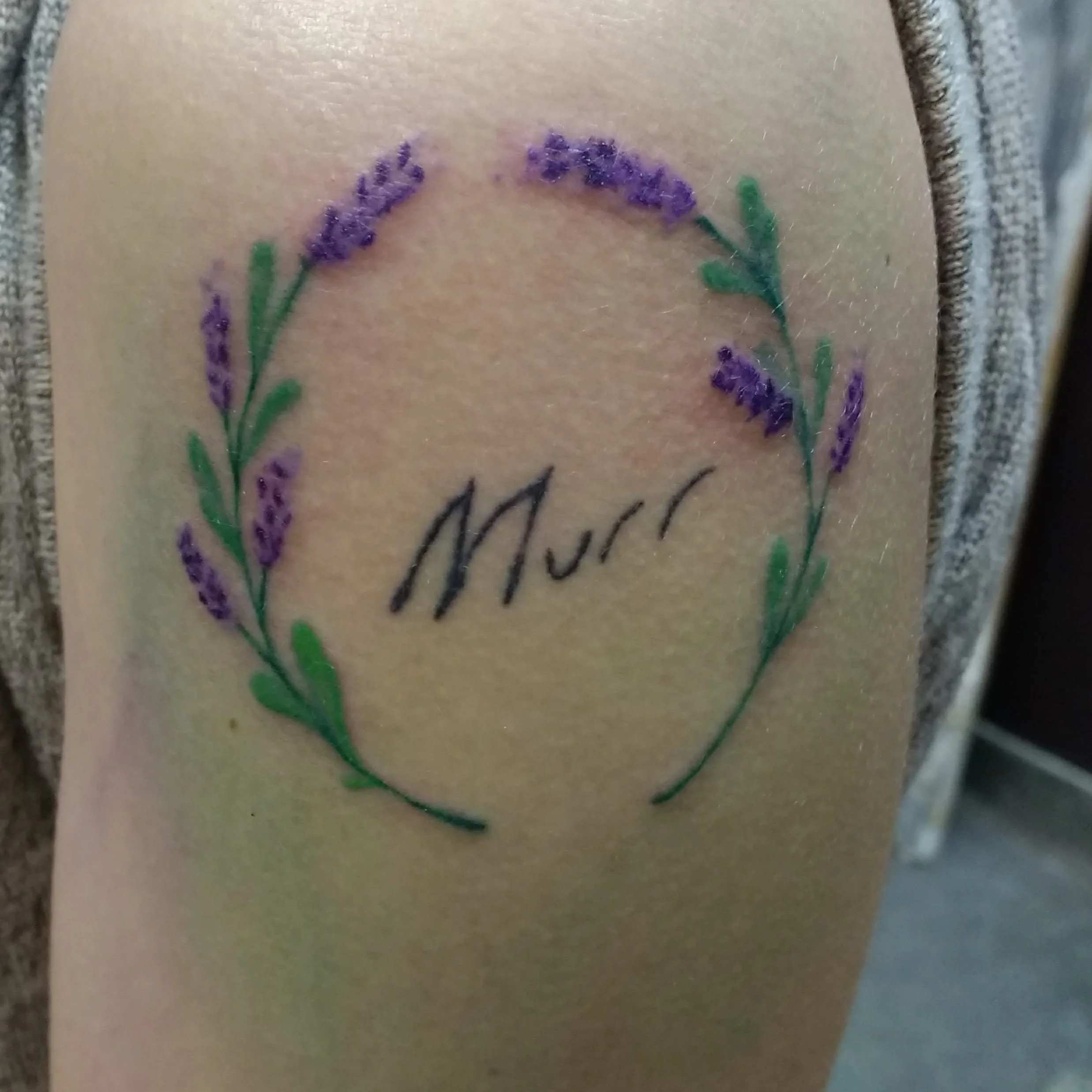 Tattoo of a purple lavender wreath with the word 'Mum' written in cursive in the center.