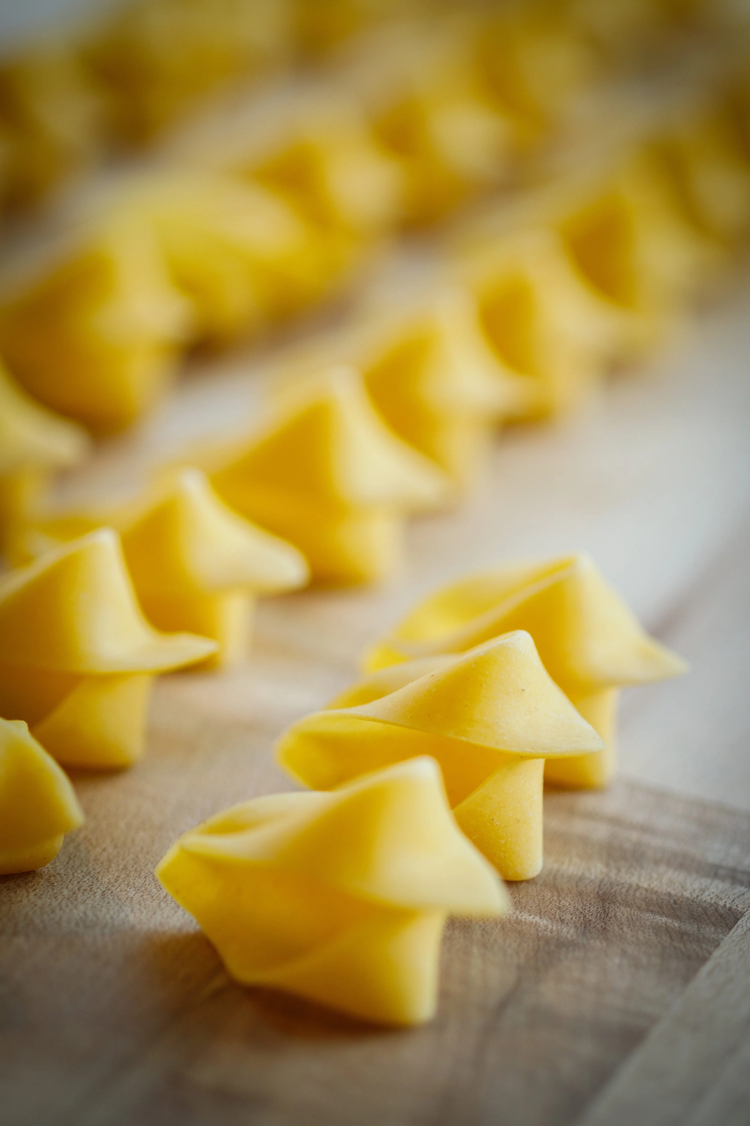 Close-up of homemade yellow pasta dough cut into star-shaped pieces on a wooden surface.