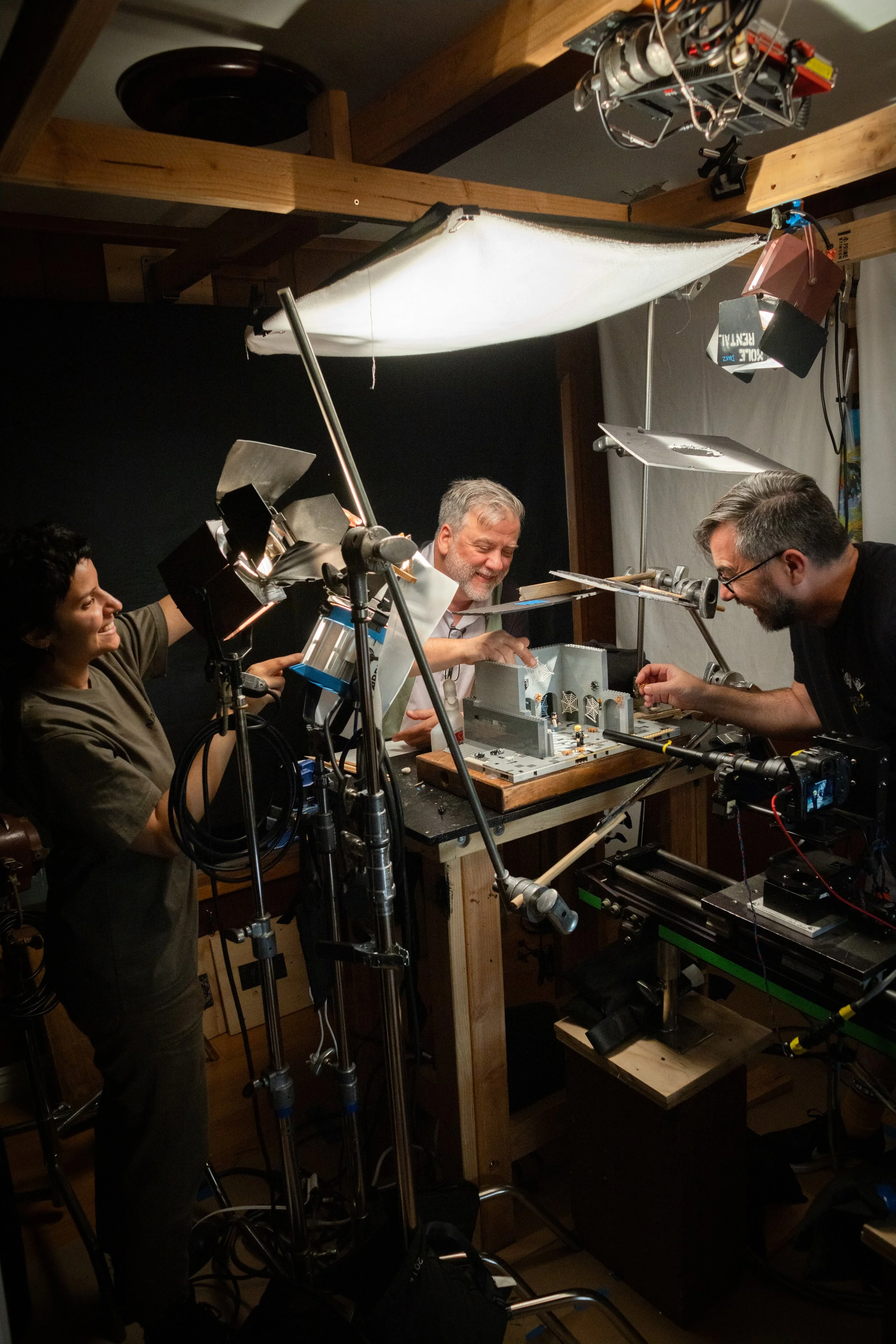 Filming crew working on a set with miniature models, lighting, and camera equipment in a studio.