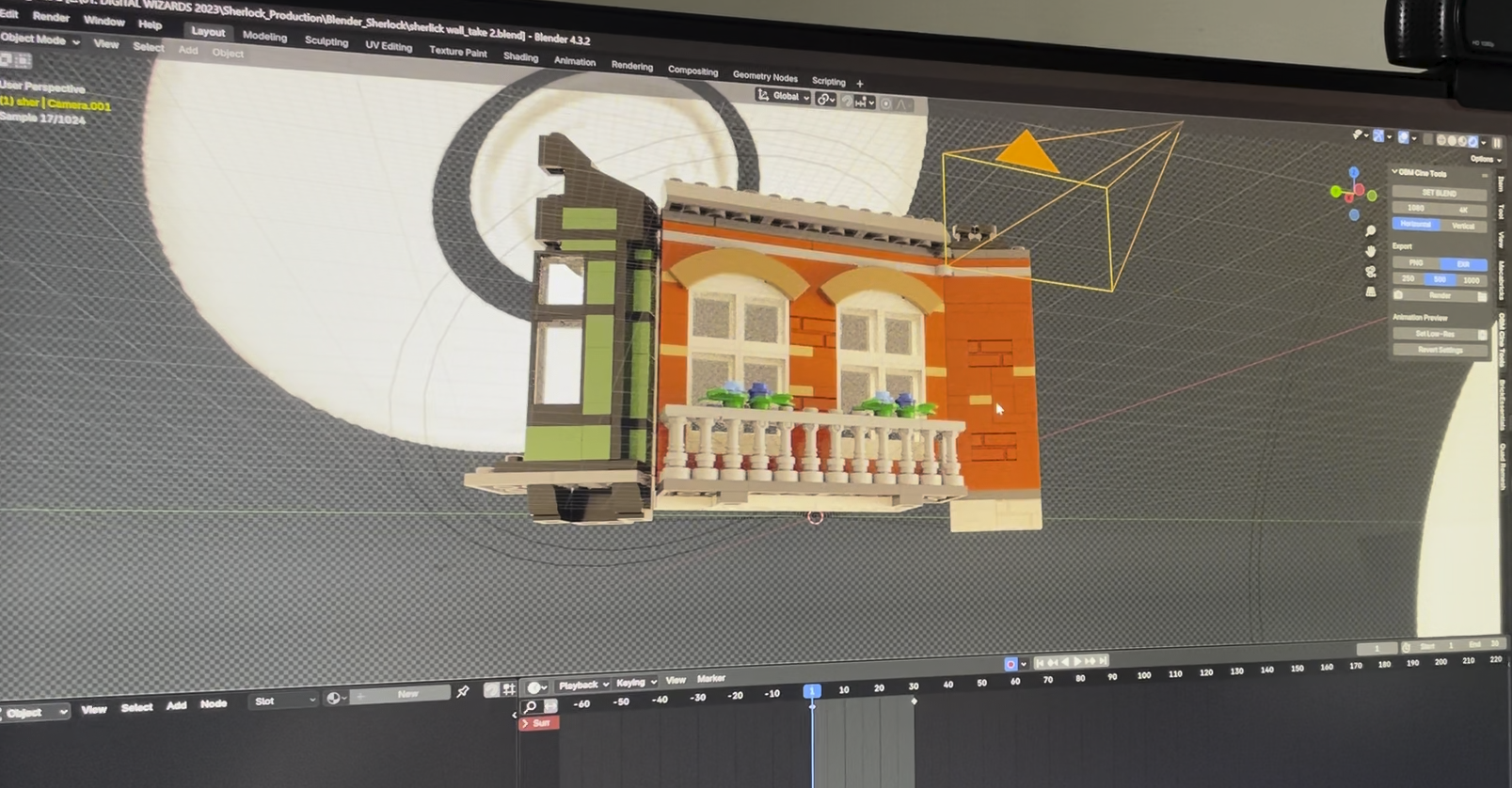 Computer screen displaying a 3D modeled house in Blender software. The house has a brick exterior, white window frames, a balcony with white railing, and potted plants. The Blender interface shows object tools and a timeline at the bottom.
