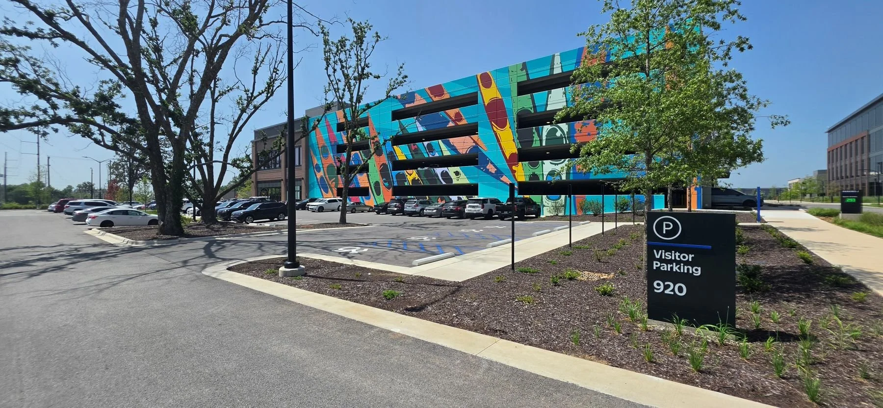 A picture of one of the Visitor Parking lots off of J street near Bentonville Bicycle Company and the parking garage that that the public can use the 1st floor and Walmart Associates can use all other floors
