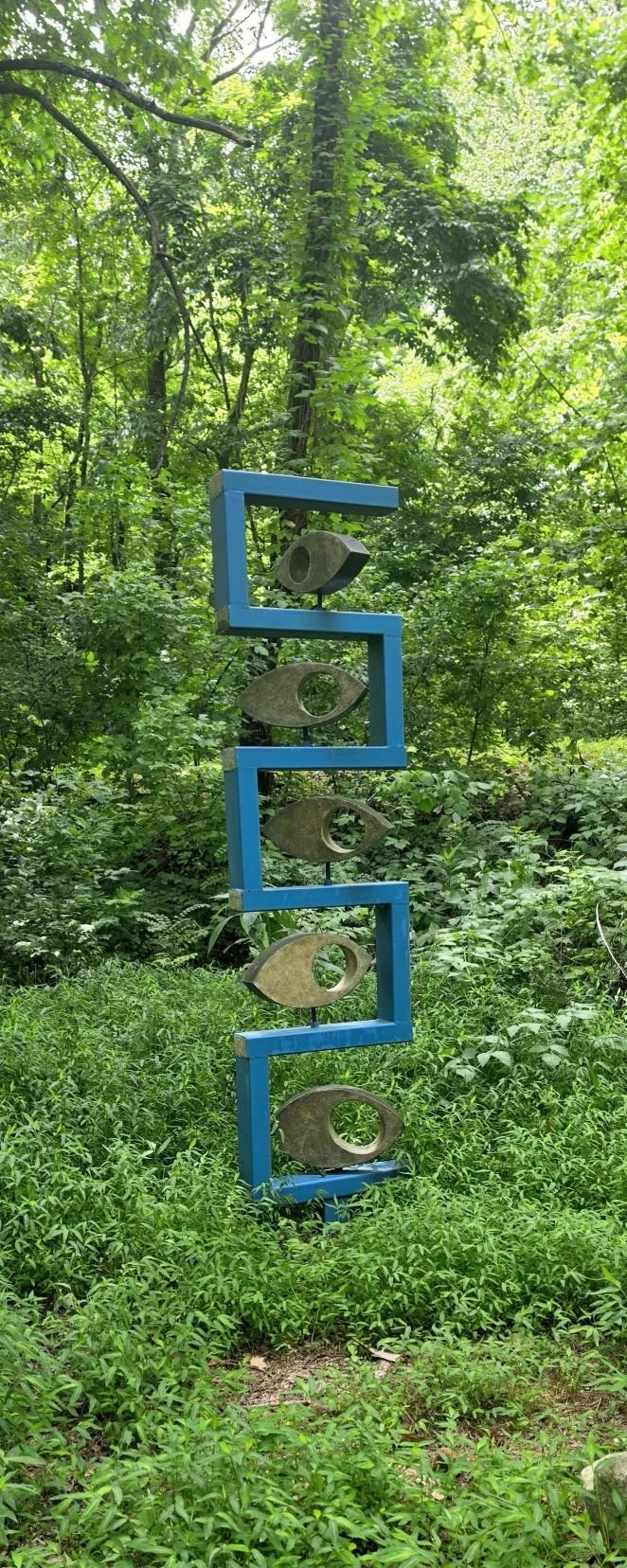 A picture of a blue sculpture that resemble 5 3 sided rectangles with some unique oblong gold colored shapes with each rectangle