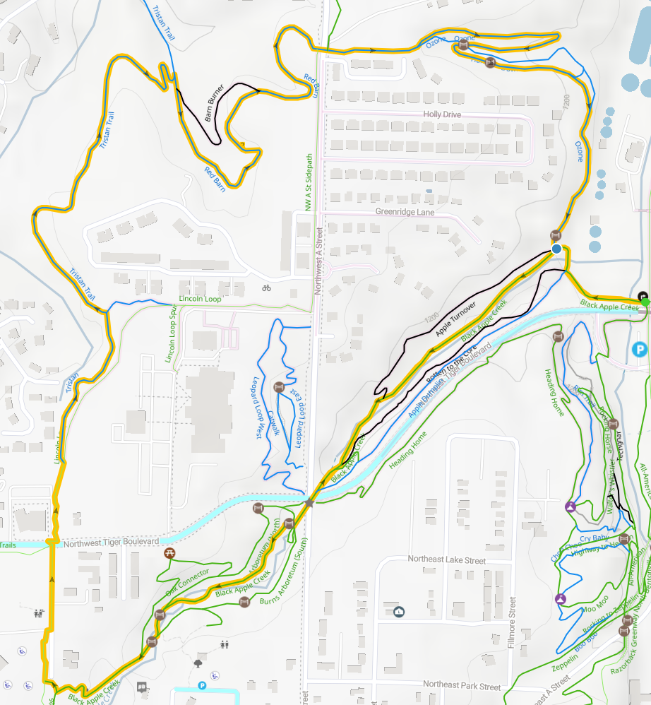 Map of a trail system with multiple paths marked in different colors, showing parks, streets, and water features nearby.