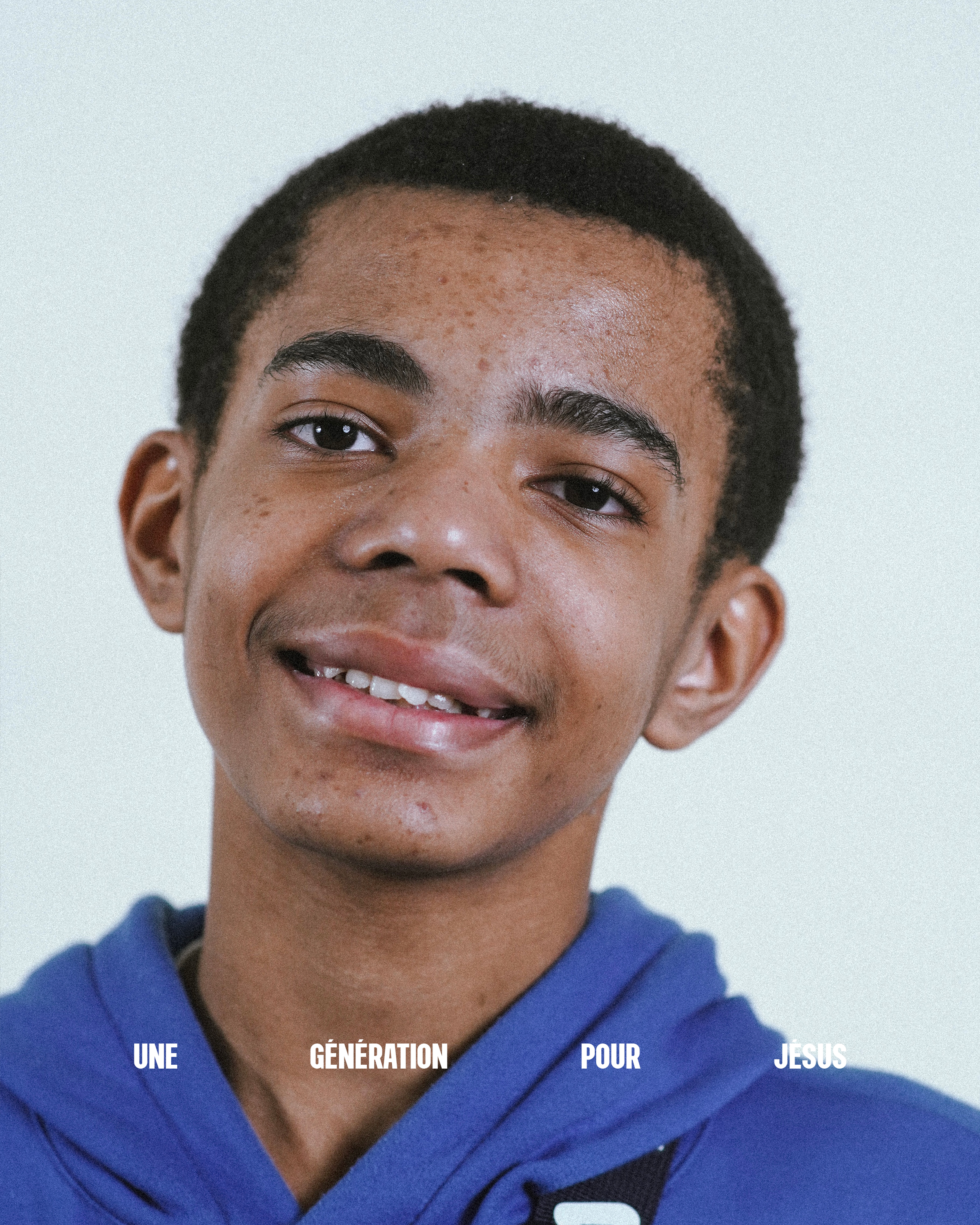Une jeune personne souriante avec des traits africains, portant un sweat bleu et un fond blanc.