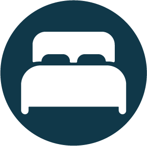 Icon of a bed within a dark circle.