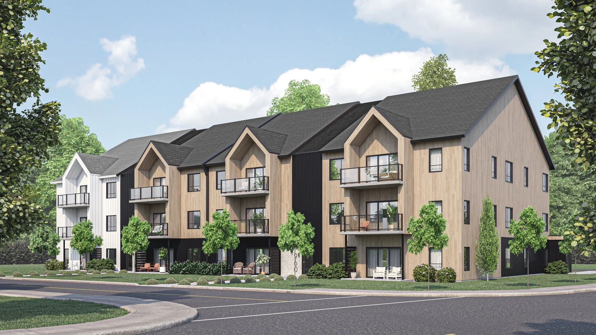 A modern apartment complex with four stories, featuring wood and black exterior siding, gable roofs, and glass balconies. The building is surrounded by green trees, a sidewalk, and a street with a curved corner, under a partly cloudy sky.