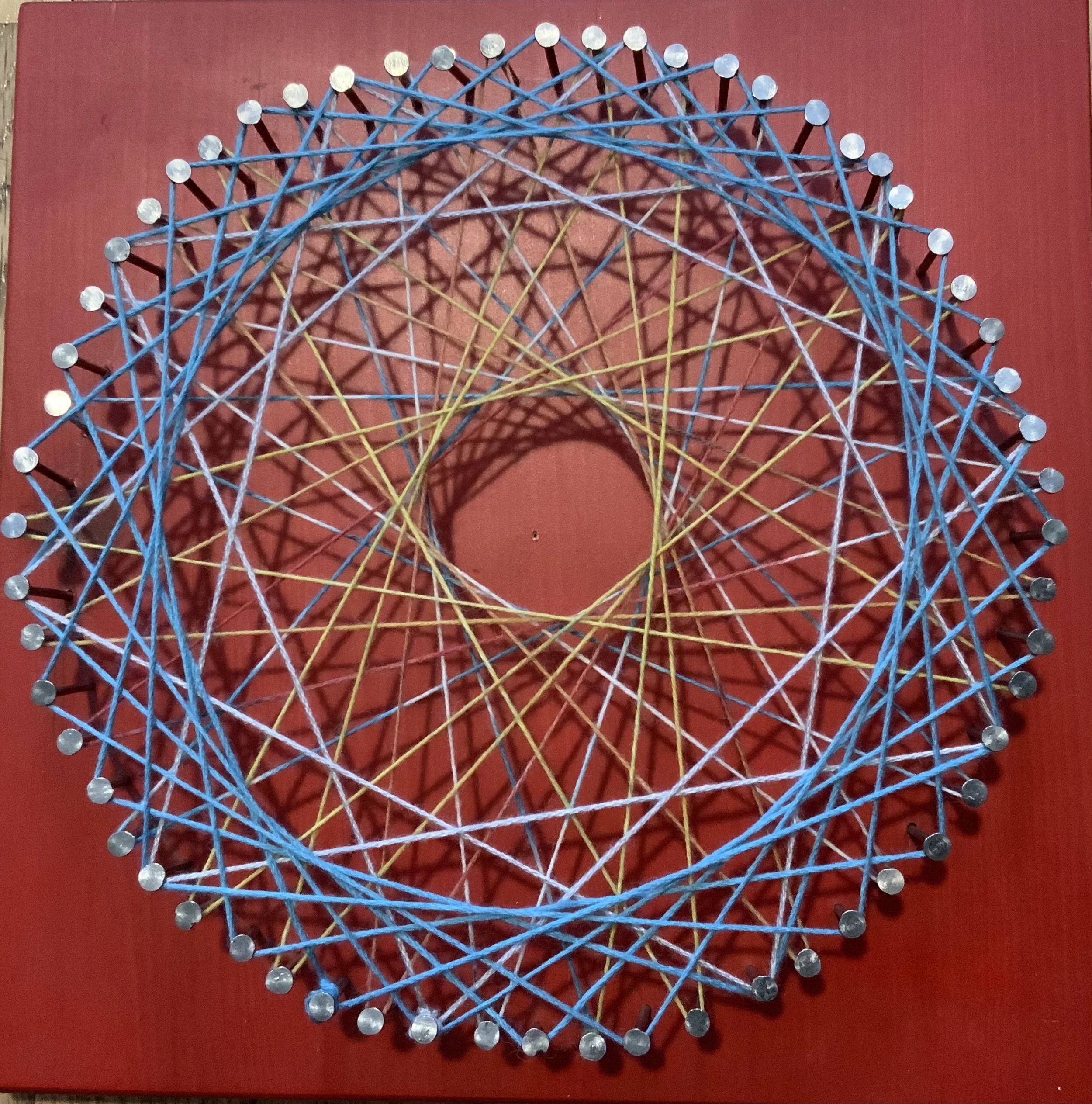 Geometric string art piece featuring colorful strings arranged in intricate patterns on a red background. (Created by O.E. Zelmanovich. Zoe Zelmanovich. Zoe Mizuho)
