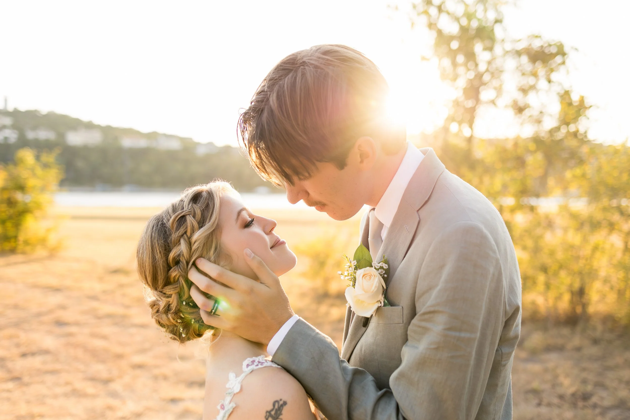 A golden-hour wedding portrait captured in a serene landscape, featuring a couple embracing beneath warm light. This image reflects a luxury outdoor wedding aesthetic with natural beauty, movement, and a refined editorial approach