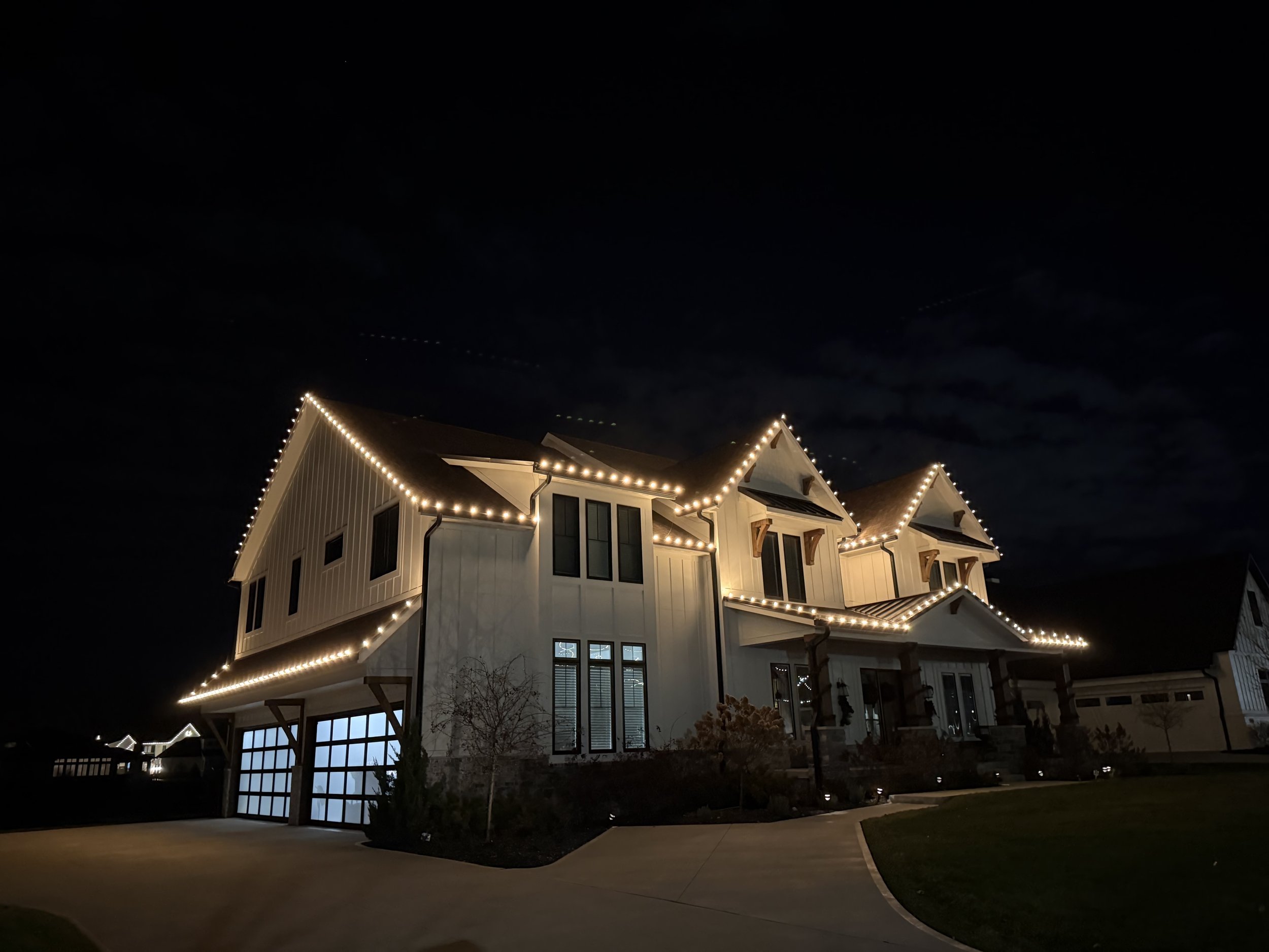 A house decorated with festive string lights at night, with a dark sky above.