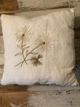 Cream-colored decorative pillow with embroidered dandelion flowers and leaves.