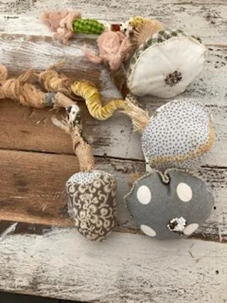 A handmade fabric doll with several soft, patterned fabric toys connected by a string, lying on a rustic wooden surface.