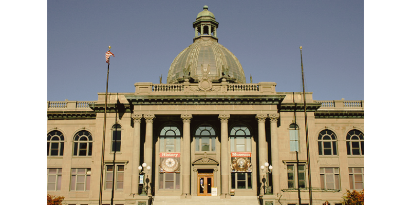 Front view of a historic government or museum building with a large dome, columns, and steps leading up to the entrance.