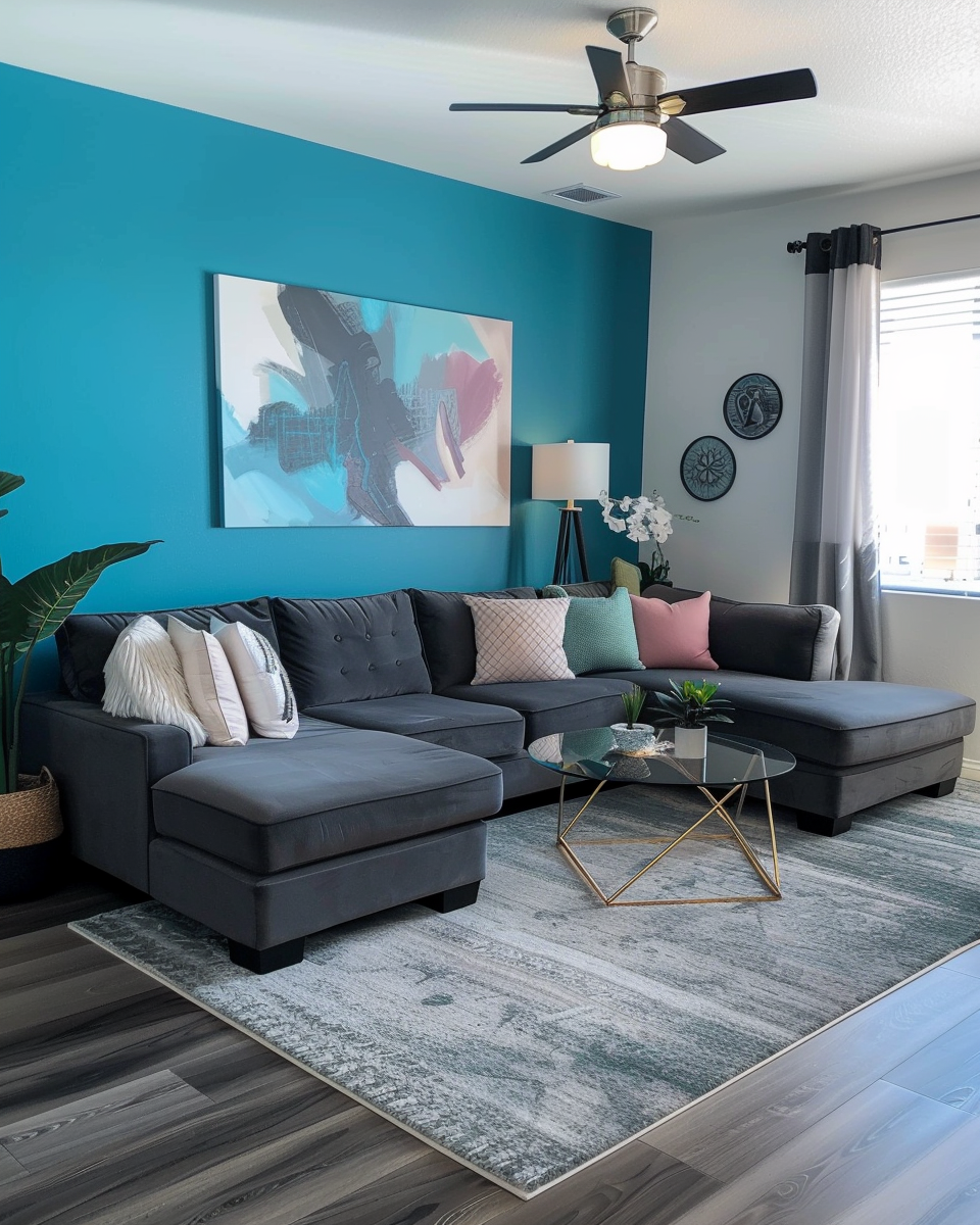 Living room with a dark gray sectional sofa, decorative pillows, a glass coffee table with a gold frame, a blue accent wall with artwork, a TV stand, a tall floor lamp, window with curtains, ceiling fan, and a patterned area rug in Knoxville home.
