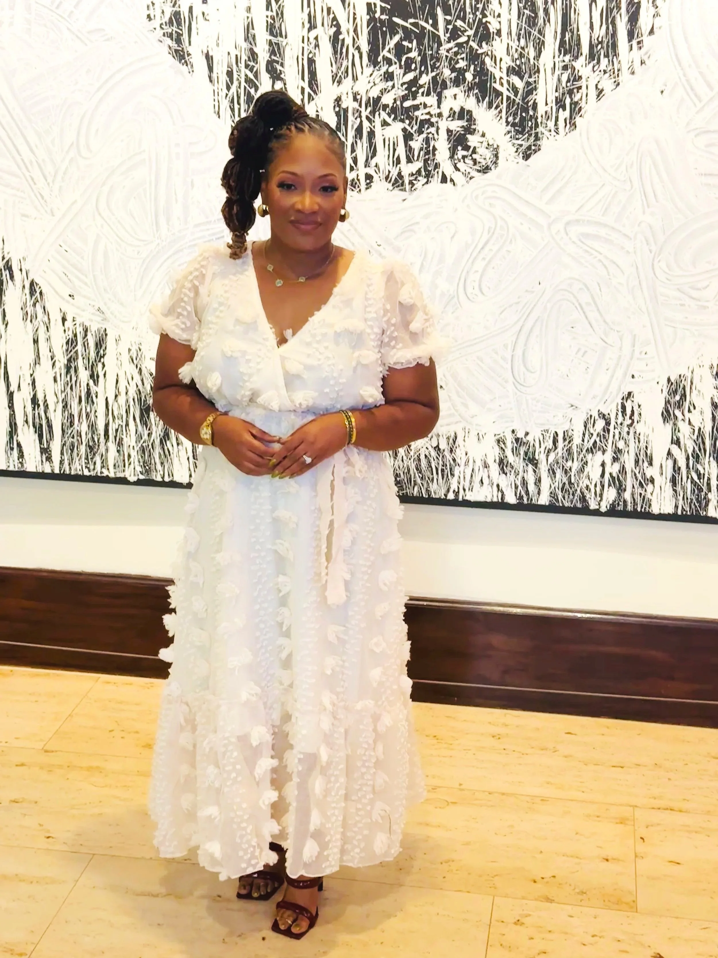 Christy Yates in a white, textured dress standing in front of modern black and white abstract artwork indoors in Knoxville.