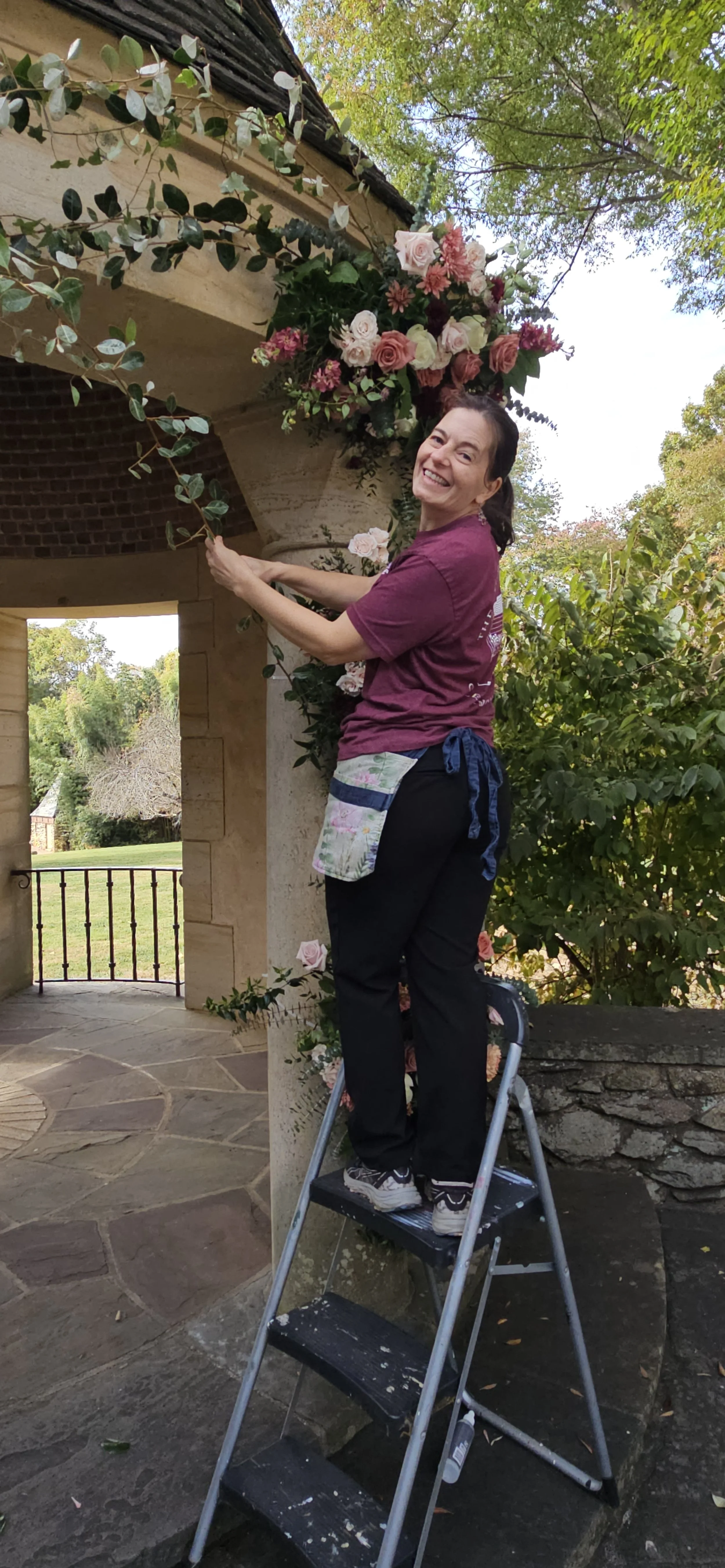 Bethany Ackiss, florist, installing floral arch piece for a Winston-Salem Wedding