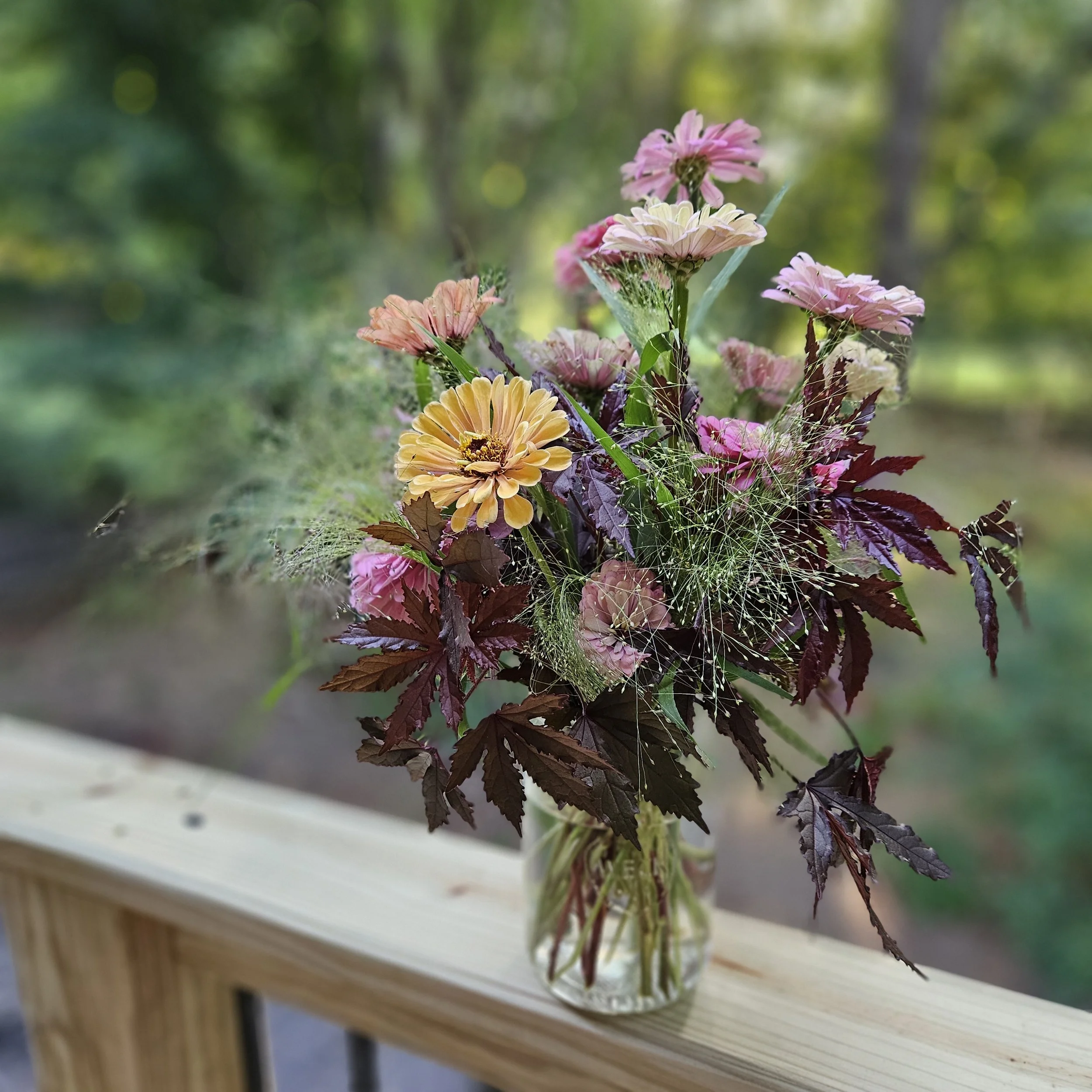 Bespoke floral arrangement of zinnias, textural grasses and mahogony splendor hibiscus for a floral workshop class