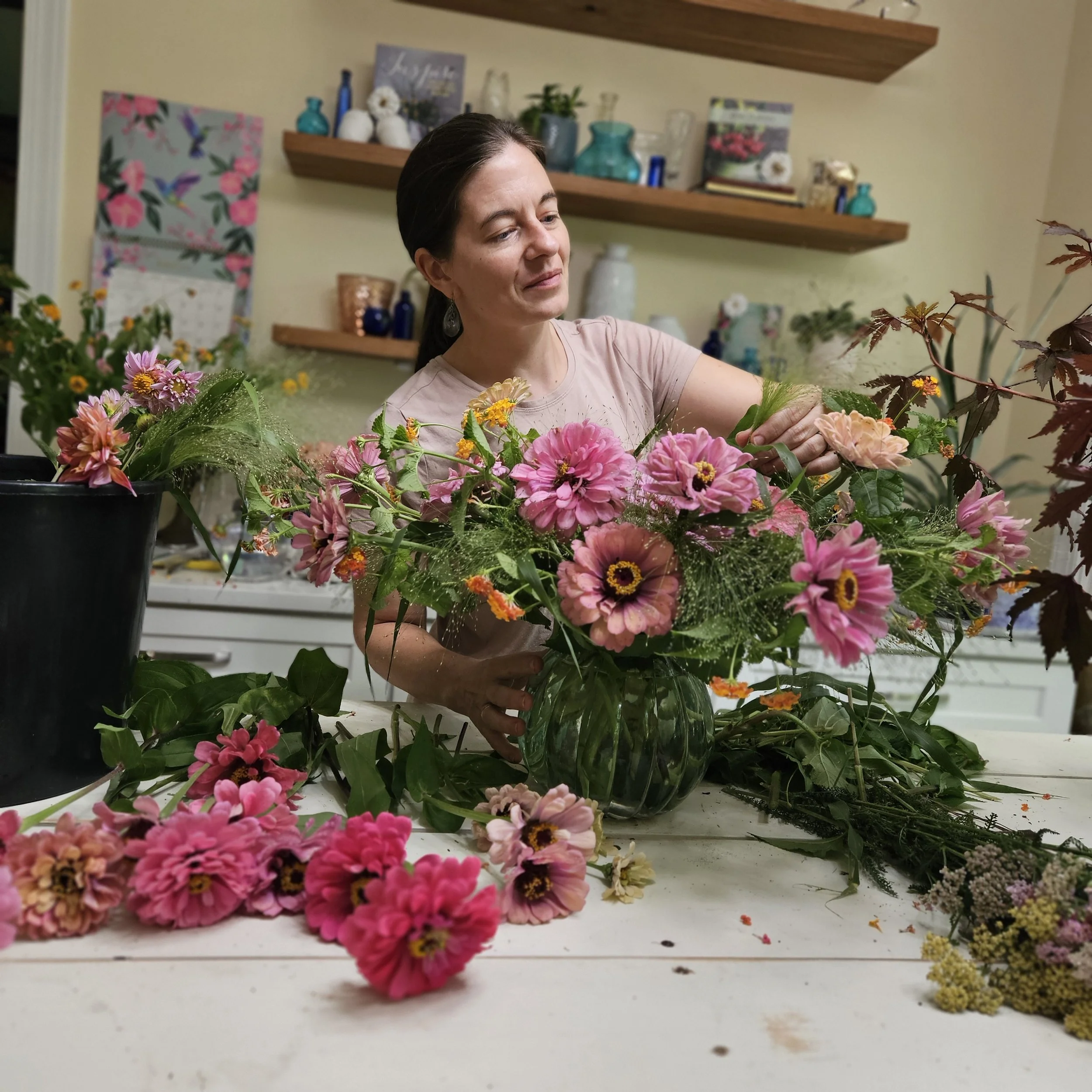 Professional florist teaching how to arrange a fresh flower arrangement of pink zinnias for a fun bridal shower activity