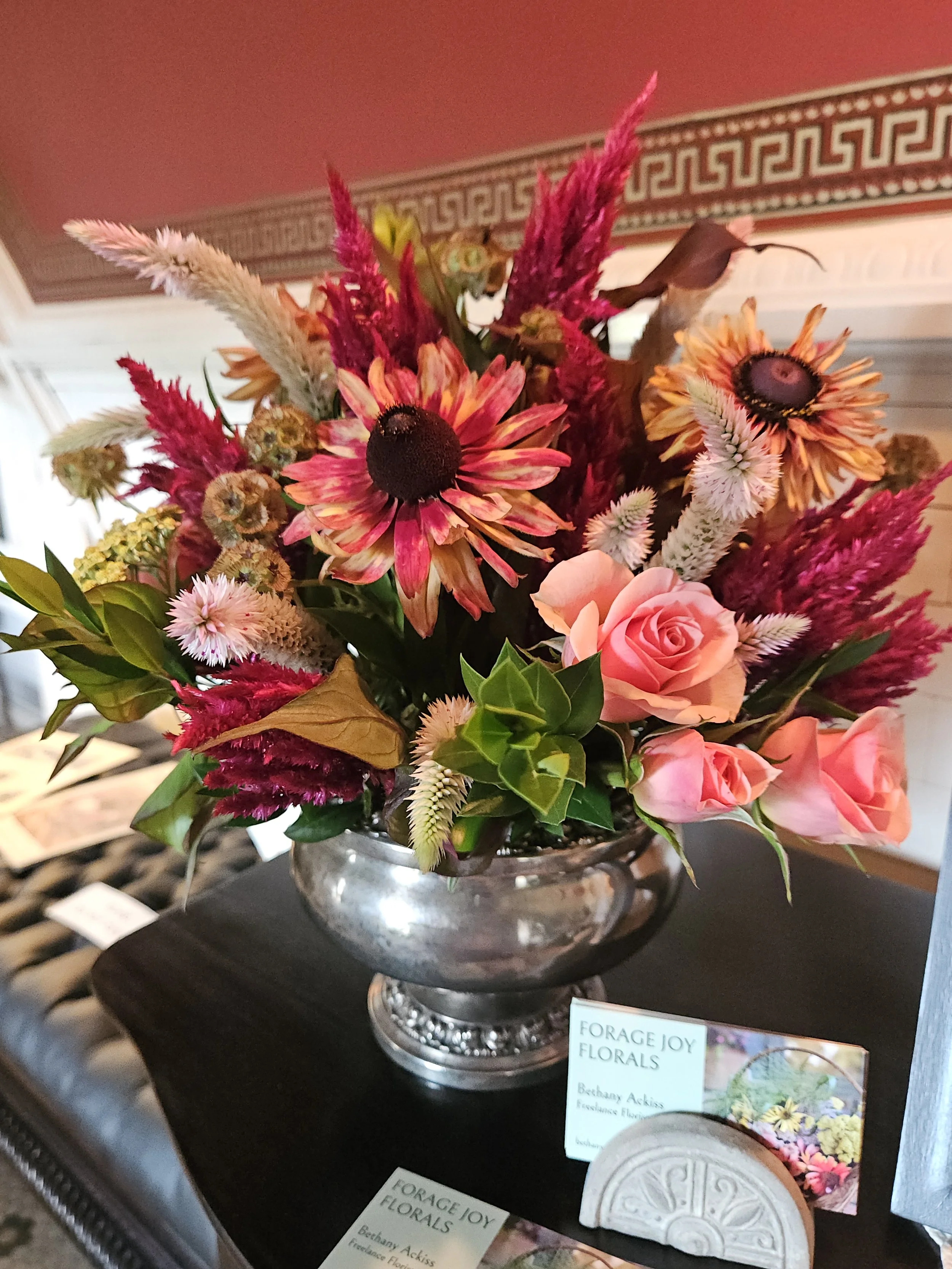 Fresh flower arrangement of vibrant mixed flowers in an antique silver vase