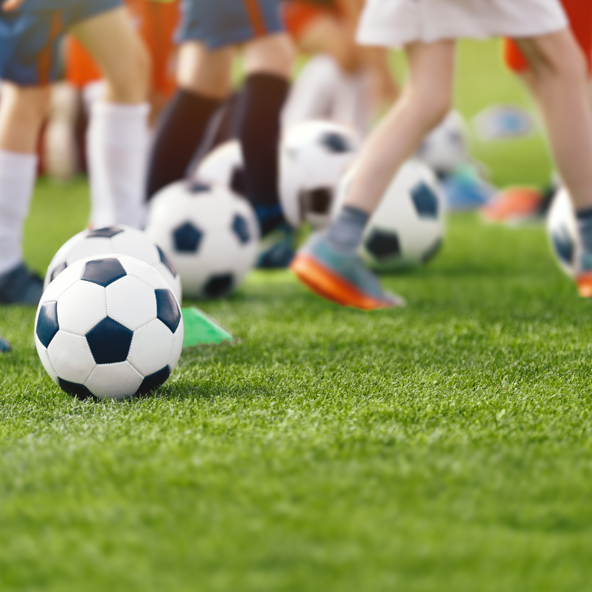 Soccer players practicing on a field with soccer balls and cones.