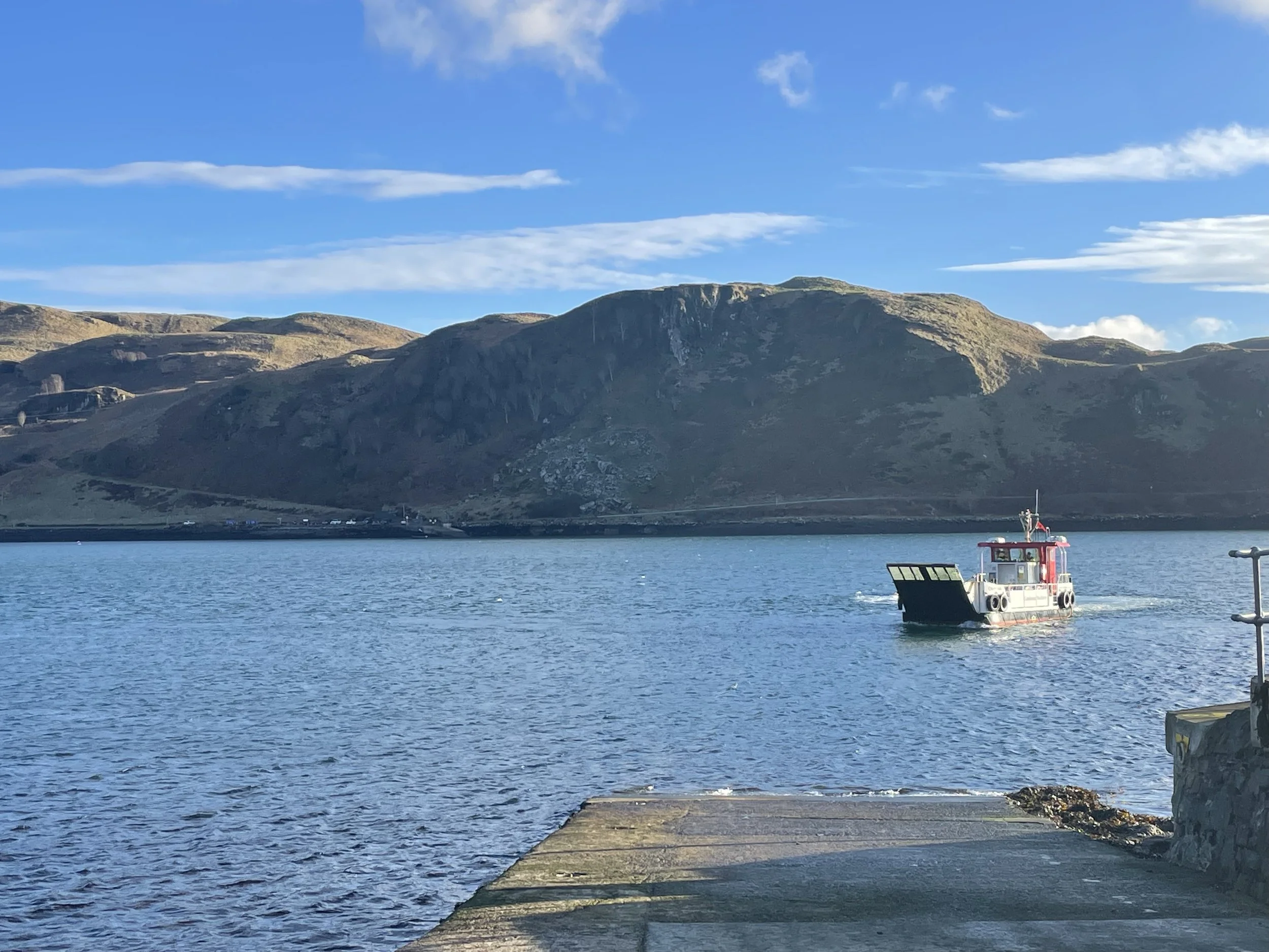 A small boat on a body of water with mountains in the background and a clear blue sky above.