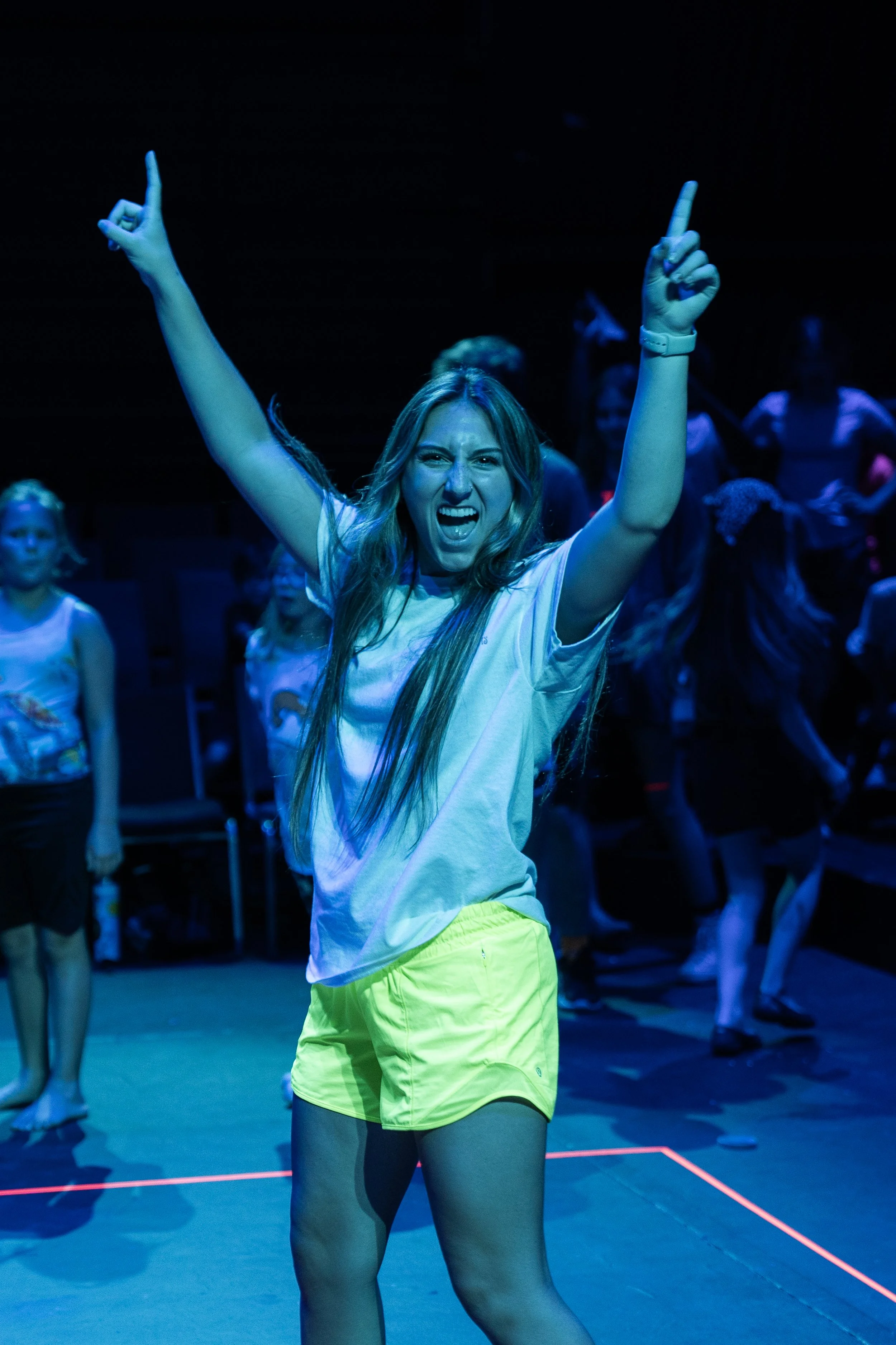 A camp counselor is celebrating a victory in a game of glow in the dark 4 square.