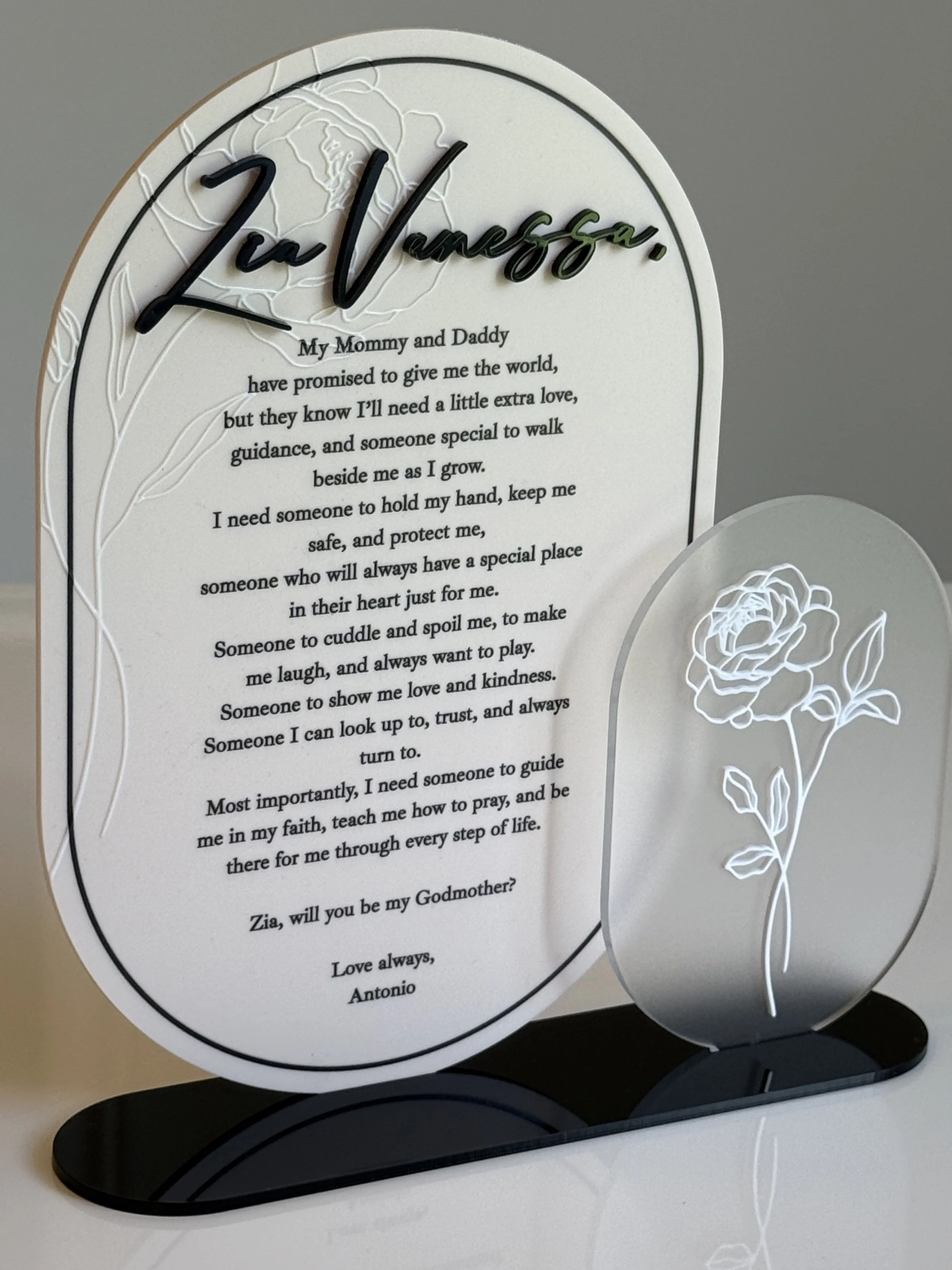 Decorative mirror with a heartfelt poem and a white floral outline engraved on its surface, resting on a black stand.