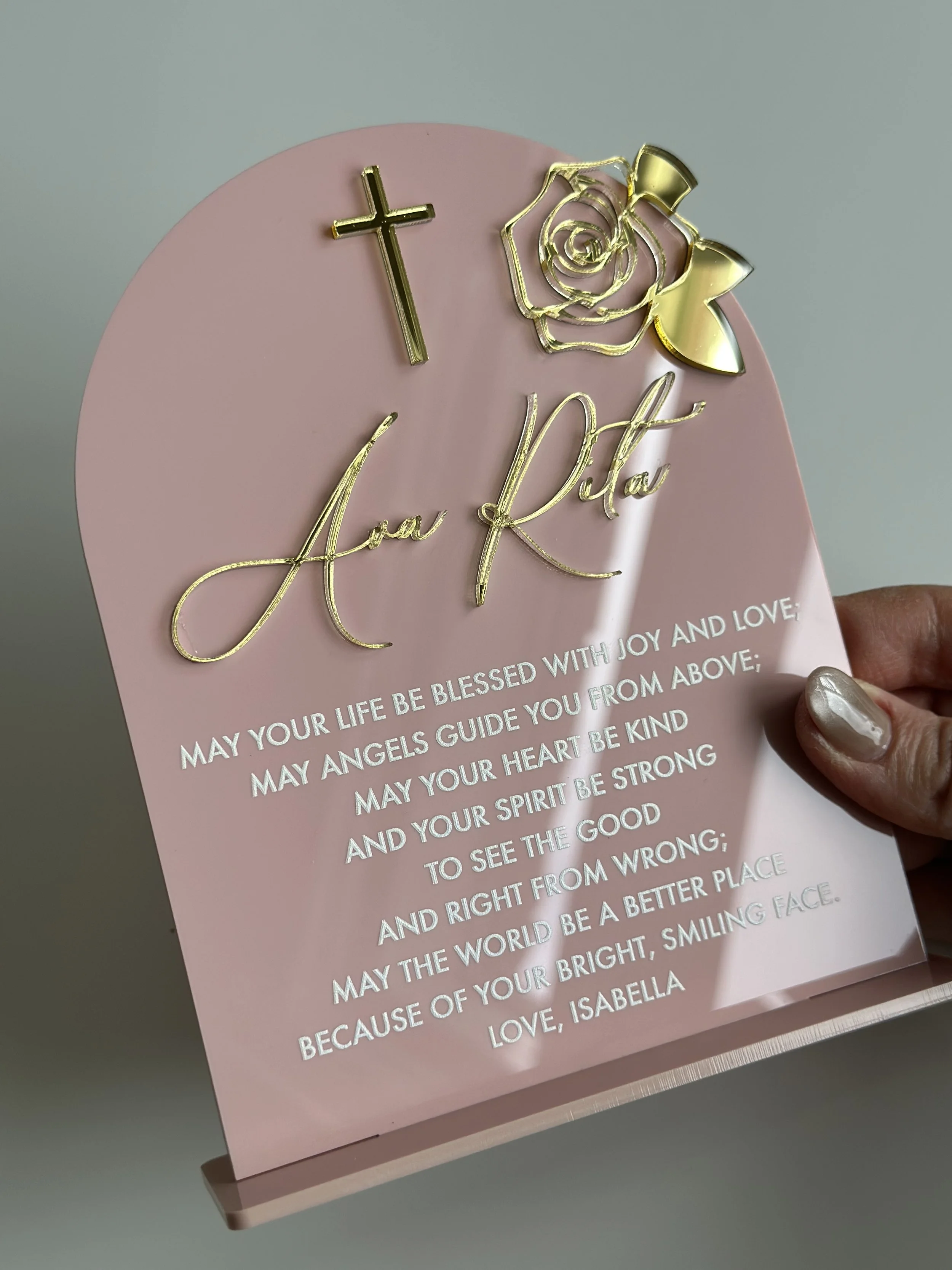 Pink memorial plaque with gold cross, rose, and inscription. The plaque features a message of blessing and encouragement, signed by Isabella.