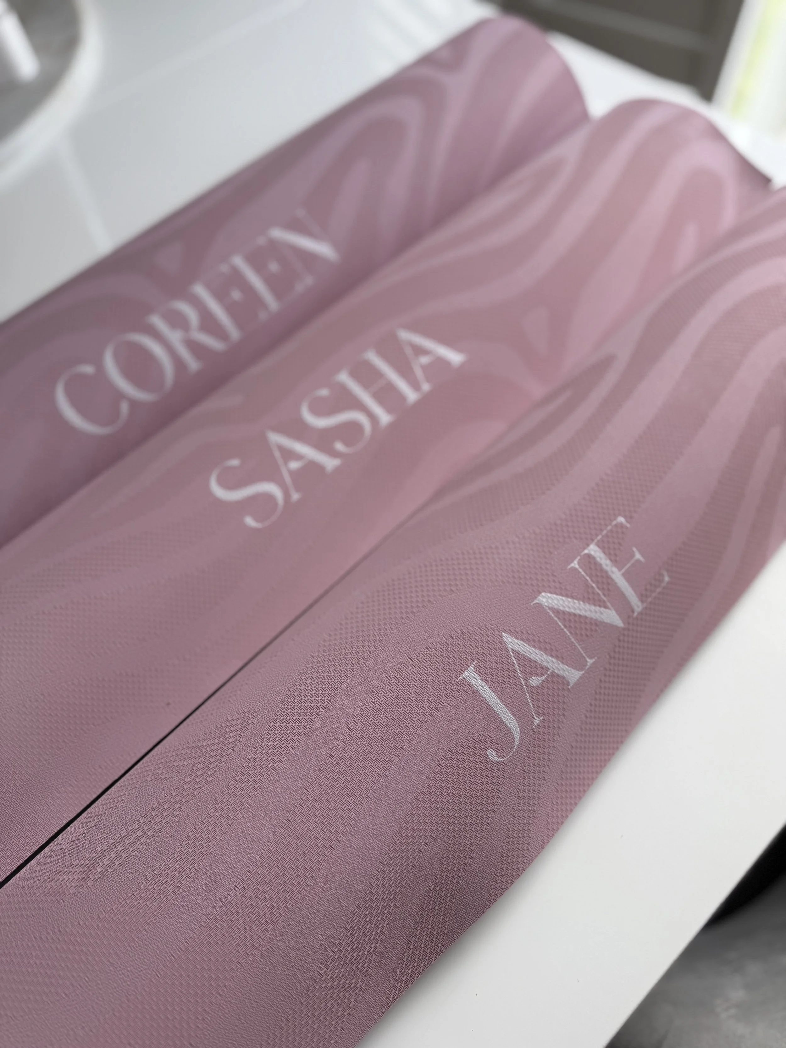 A pink laundry basket with the words "CORINE SASHIA JANE" in white letters on the side.