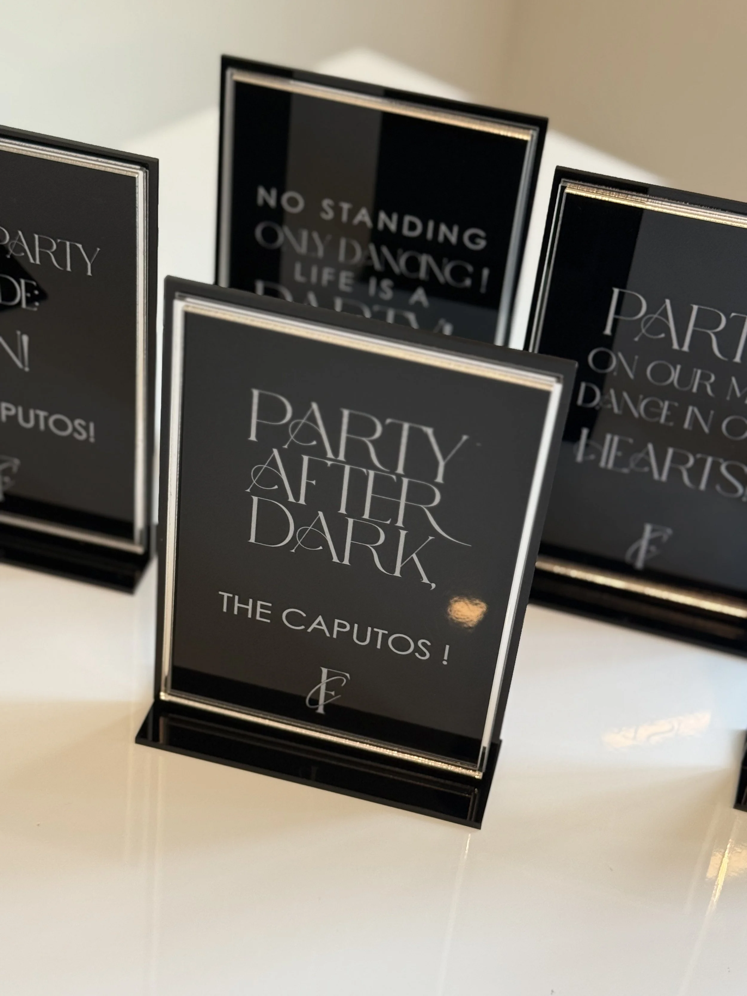 Black and white sign with elegant text that reads, 'Party After Dark, The Caputos!'
