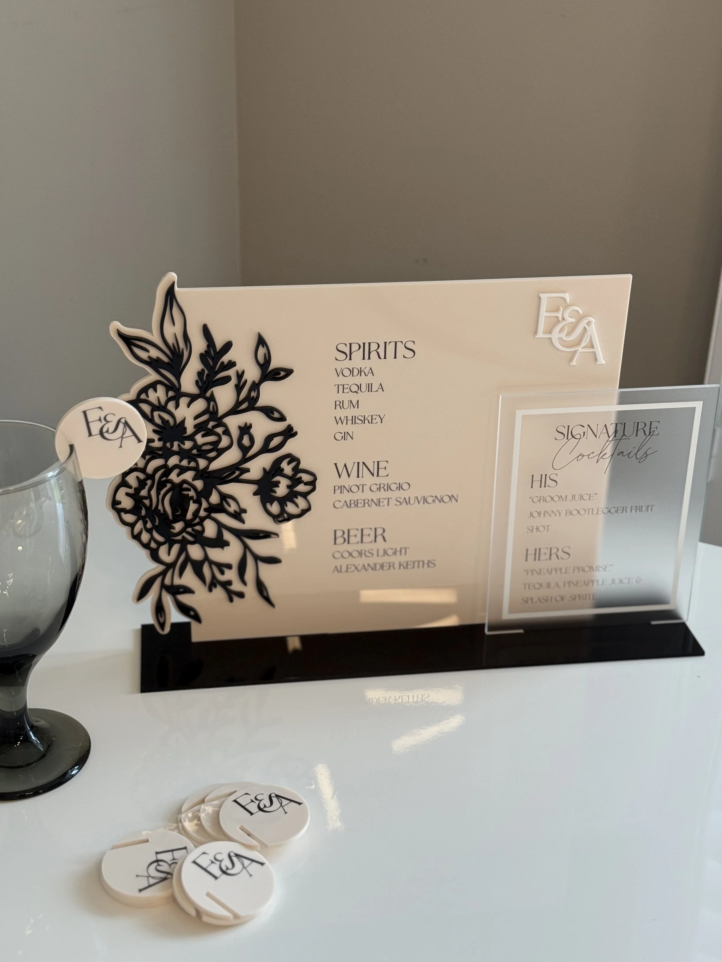 Bar drink menu with sections for spirits, wine, and beer on a white table, with drink tokens and a glass nearby.
