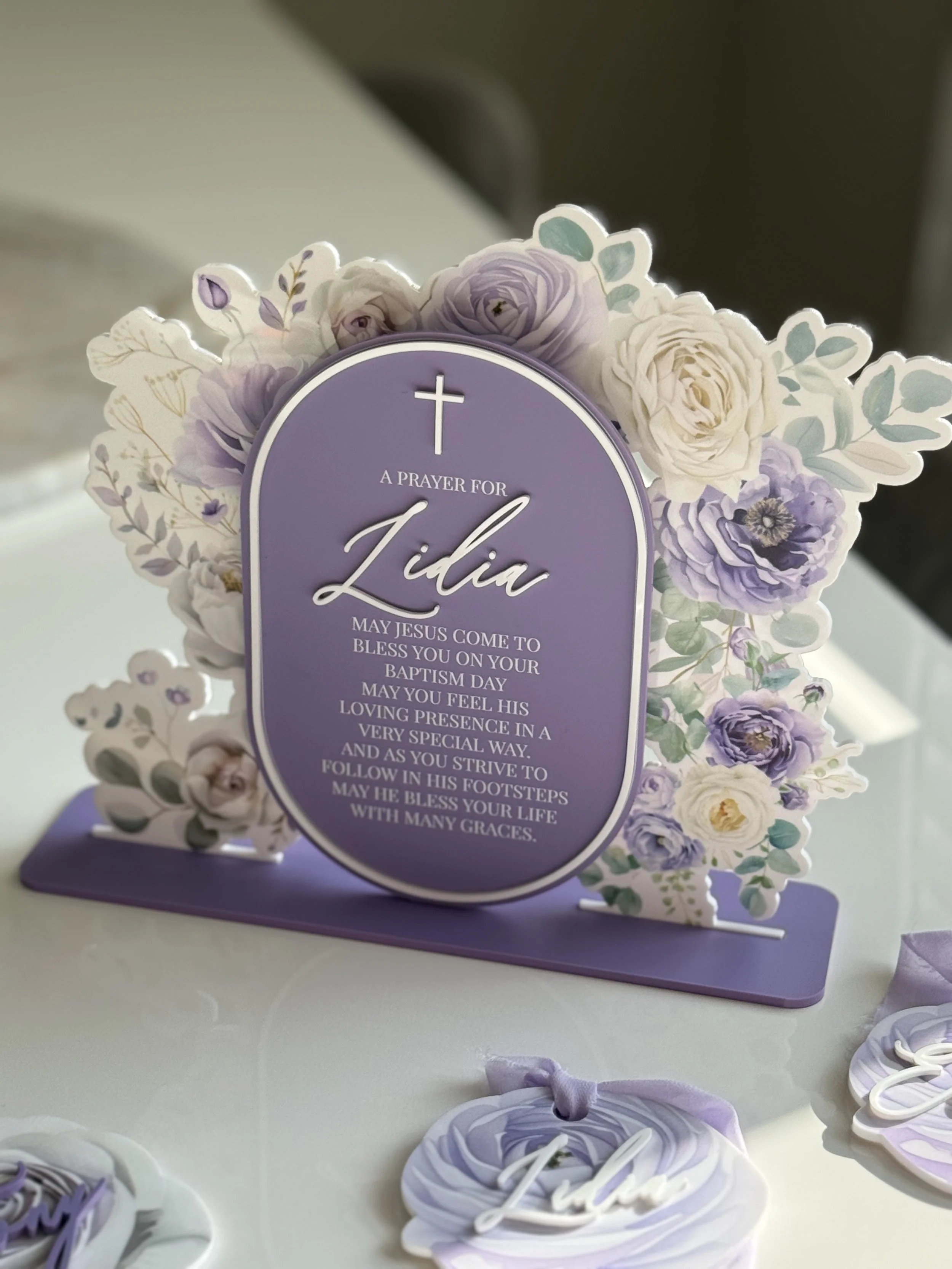 A purple prayer card with floral border and cross, reading a prayer for Lydia's baptism day.