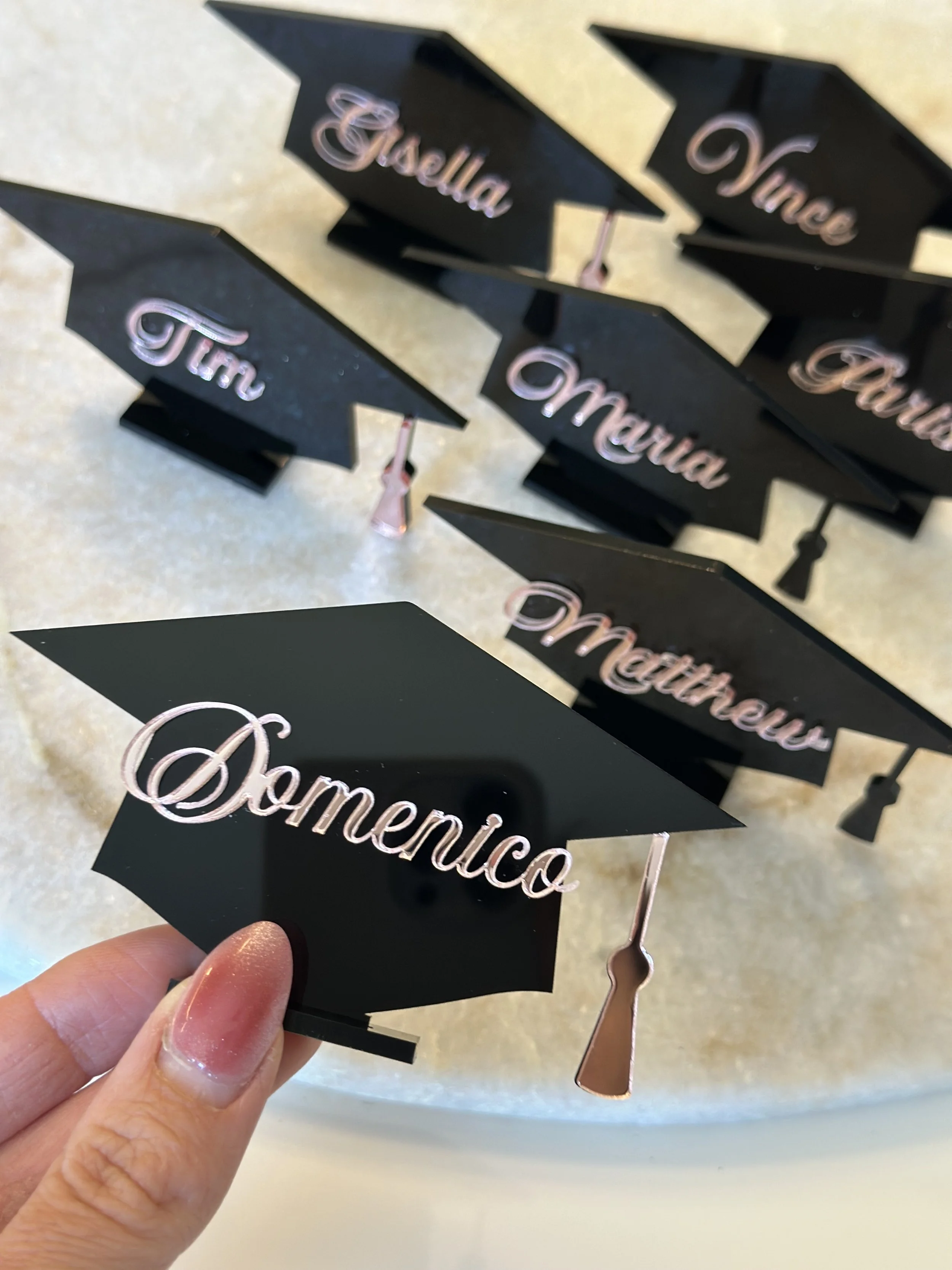 Miniature graduation cap ornaments with name tags reading 'Sematico,' 'Tim,' 'Martha,' 'Vince,' and 'Pau.'
