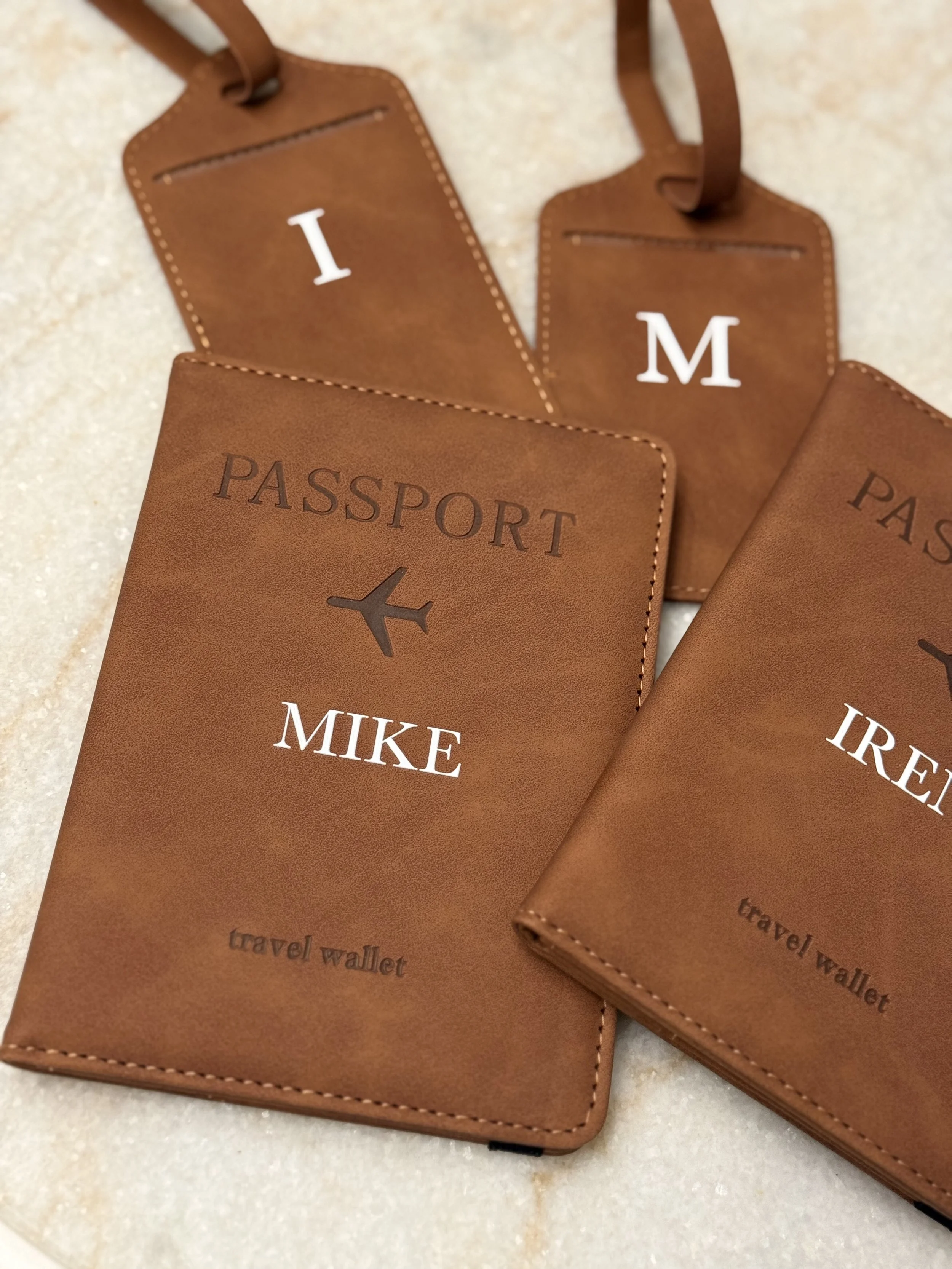 Personalized brown leather travel wallets with white names: MIKE, IRENE, and M.