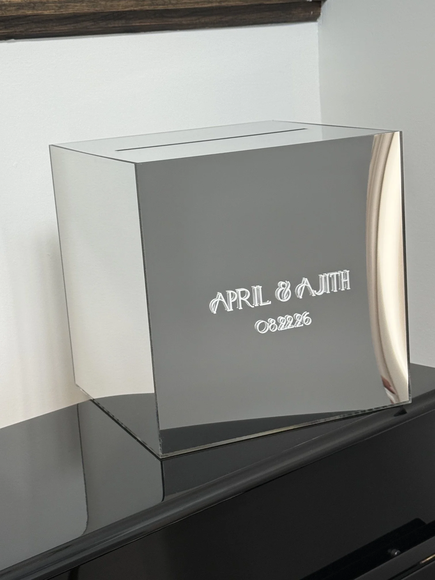 A reflective surface with words engraved on it reading 'April & AJH 08.22.26'.