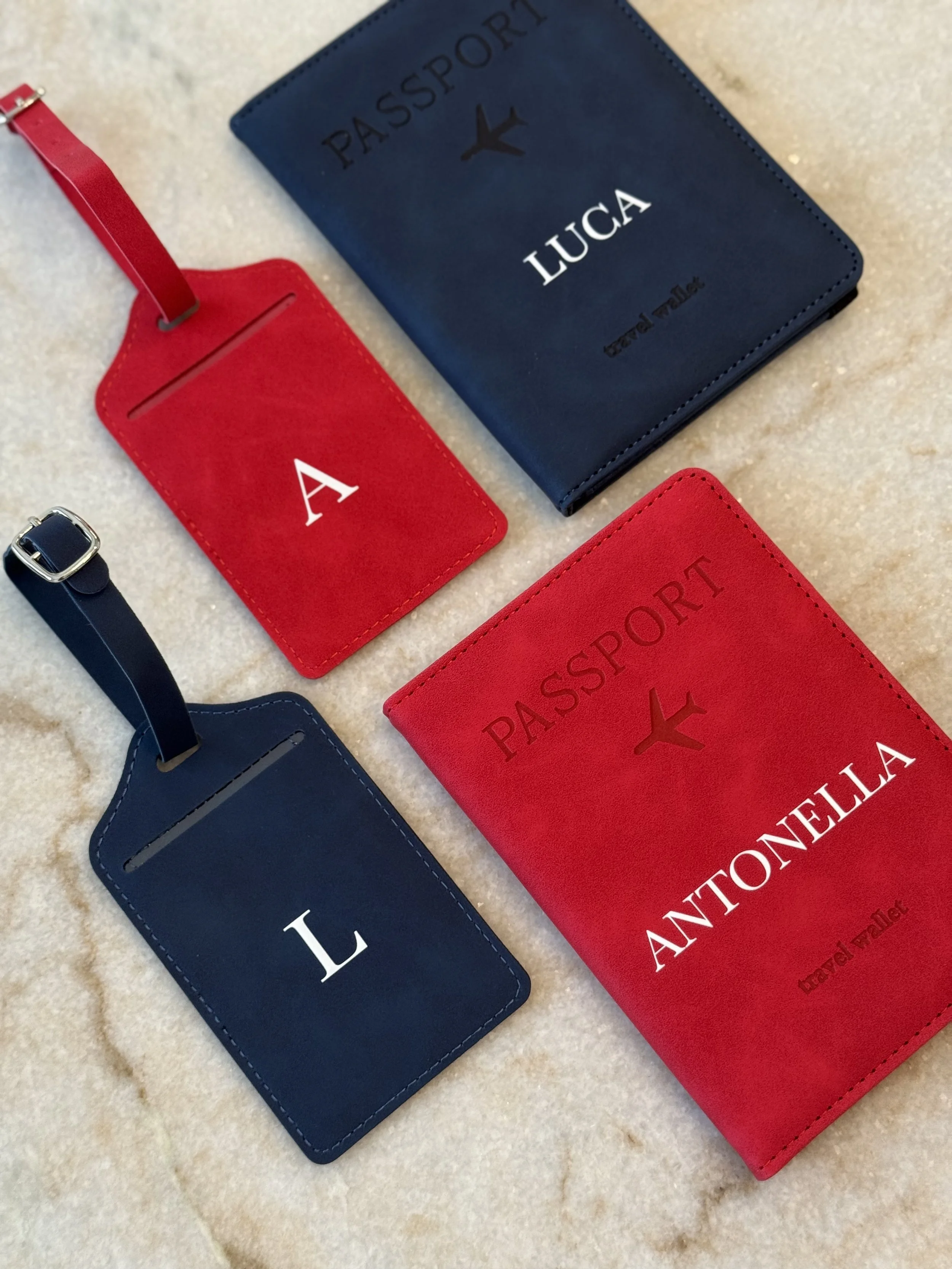 Collection of travel accessories including a blue passport holder, red luggage tags, and a red passport cover displayed on a light surface.