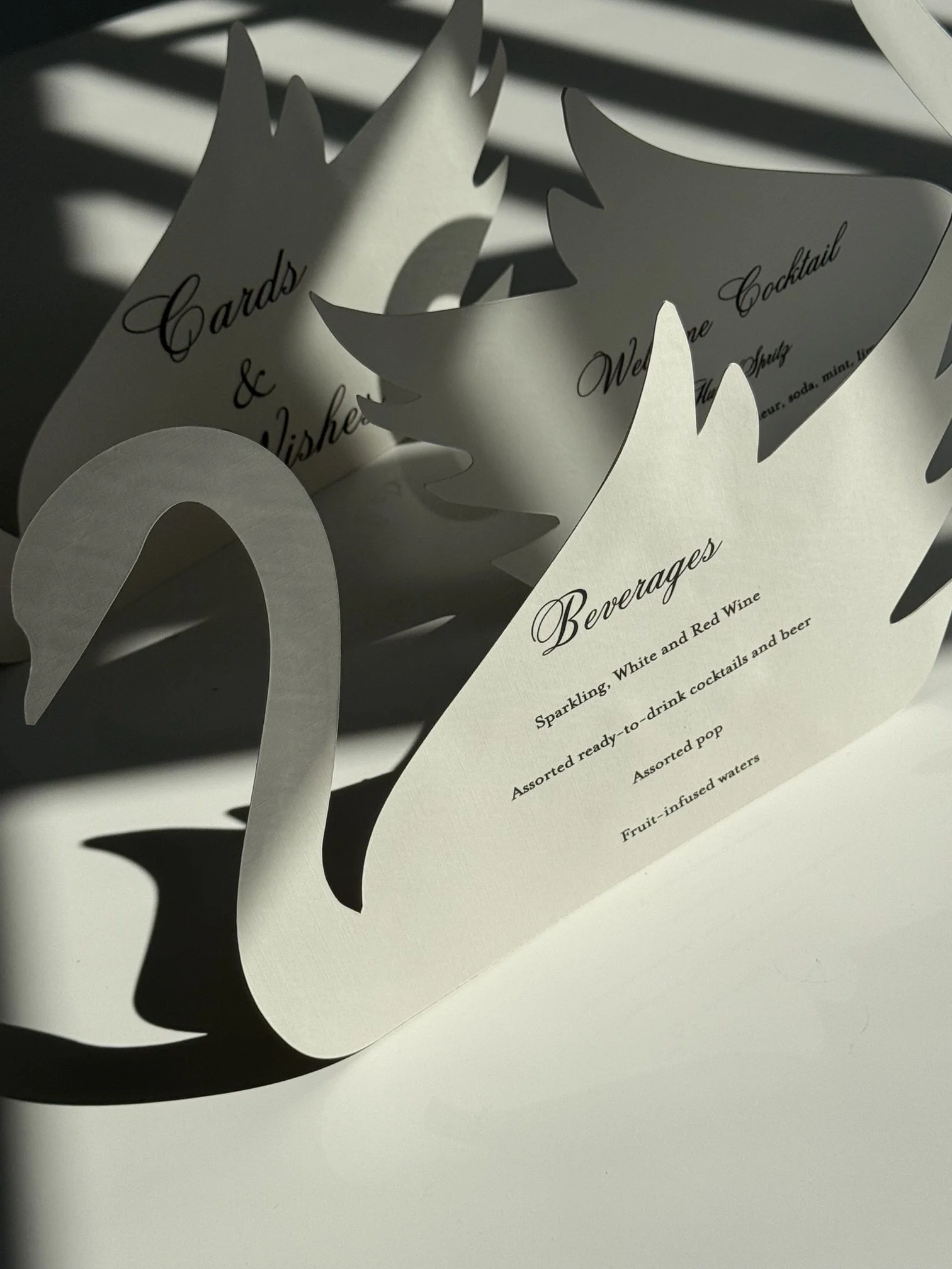 A white, decorative paper sign with cut-out star and moon shapes, listing menu categories such as 'Cards & Wishes,' 'Wedding & Bridal,' and 'Beverages' with text about sparkling wines, cocktails, and other beverages.